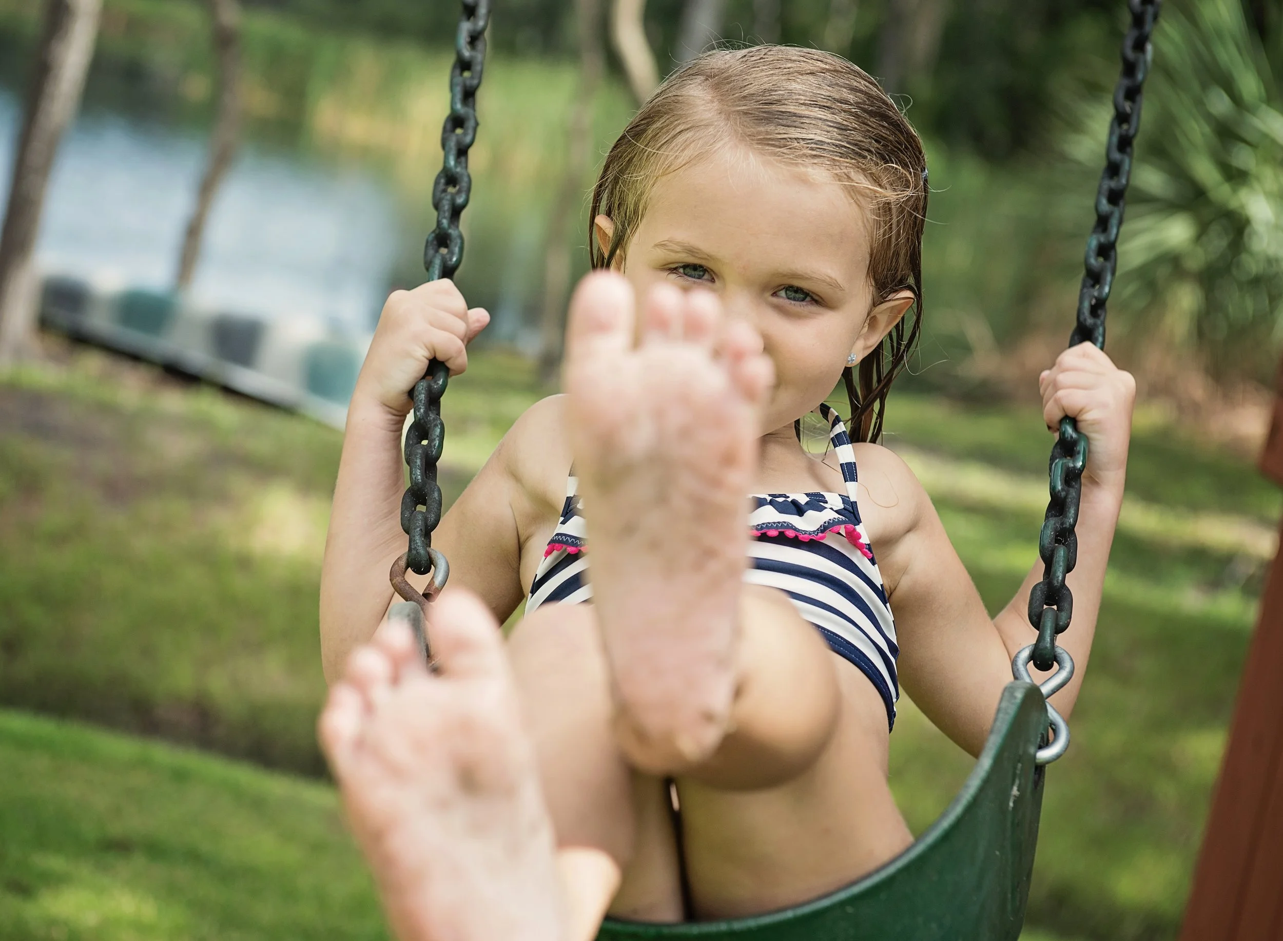 Young girl in bathing suit on a swing in her backyard