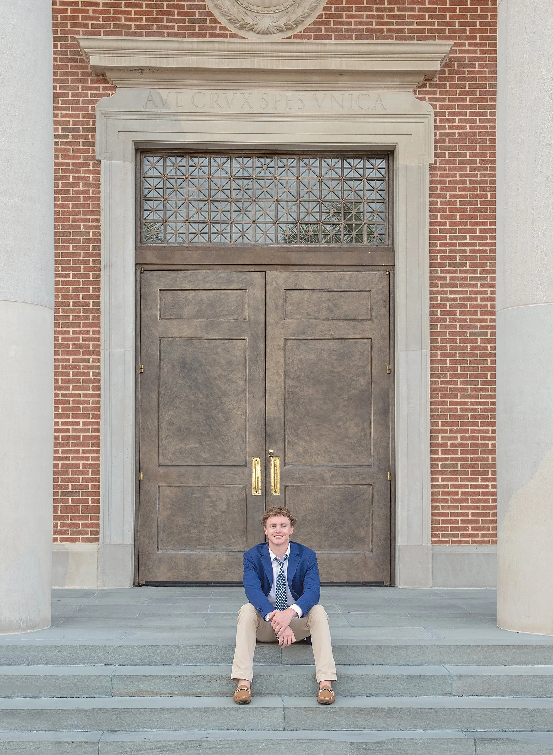 Teen boy sitting on the steps in front of the church at Jesuit High School in Tampa