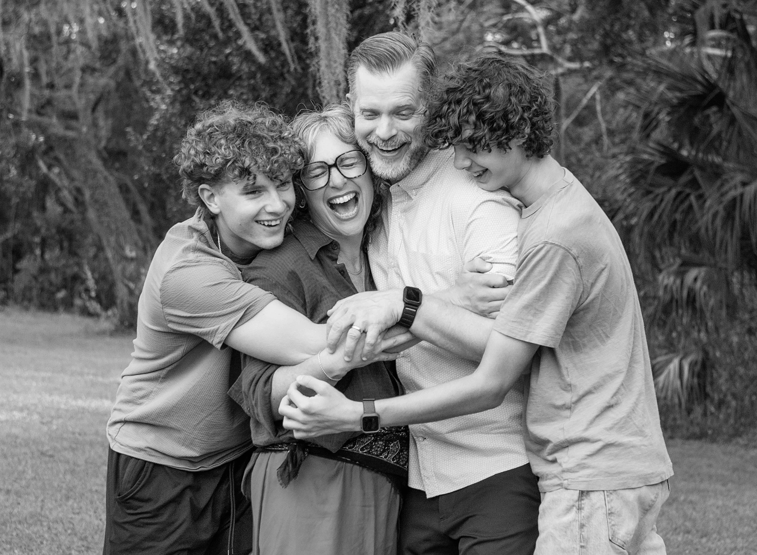 Family of four, including two teenage boys, hugging and laughing