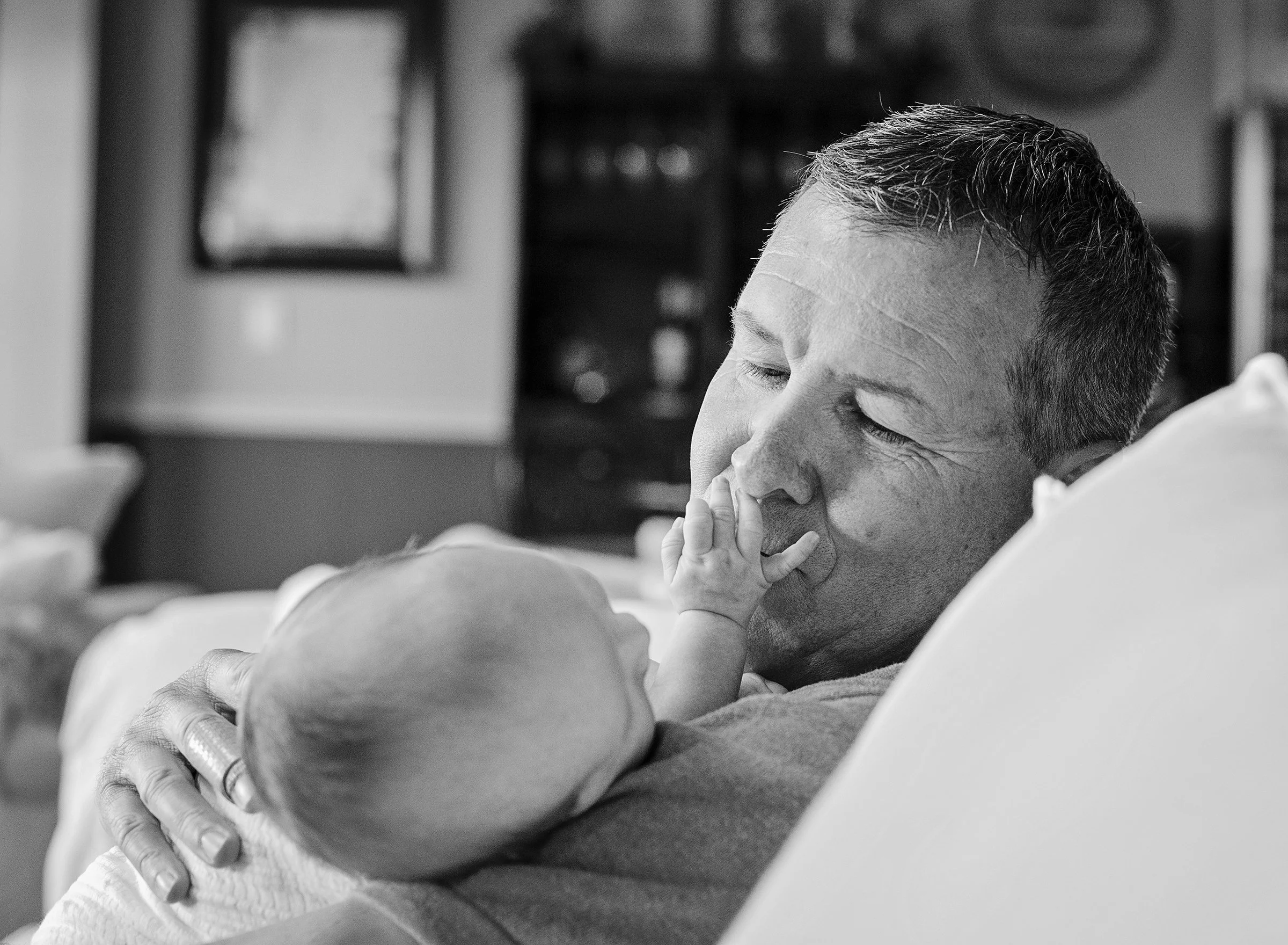 Man holding a newborn baby and kissing his hand