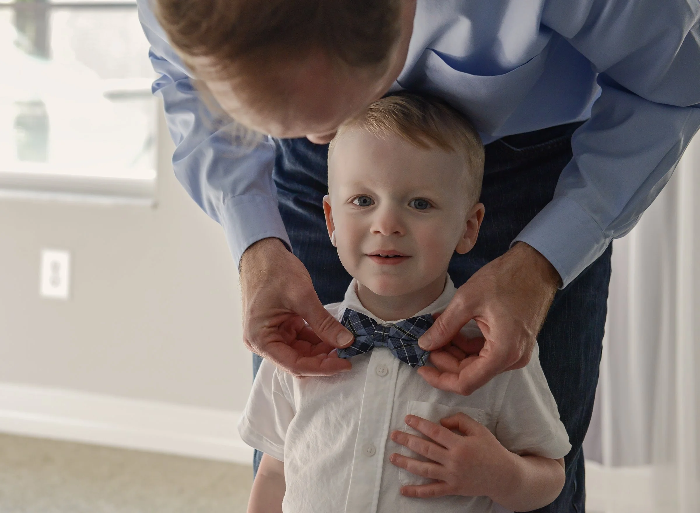 Man leaning over young boy fixing his bowtie