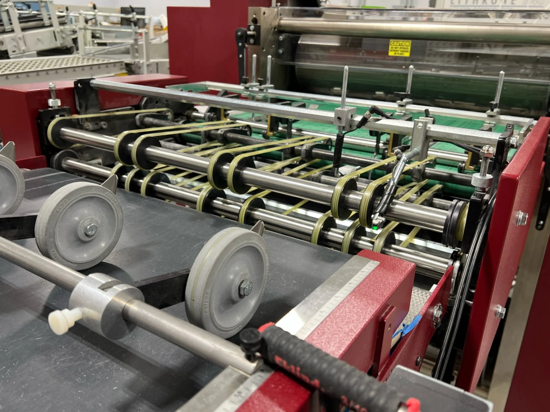 Close-up of an industrial machine with rollers and metal parts, possibly used for manufacturing or processing materials.