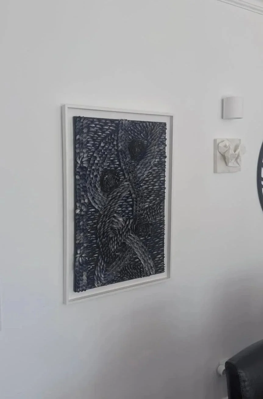 Wall-mounted framed artwork with intricate abstract black and white patterns, made of natural Mussel shells ,white wooden frame.