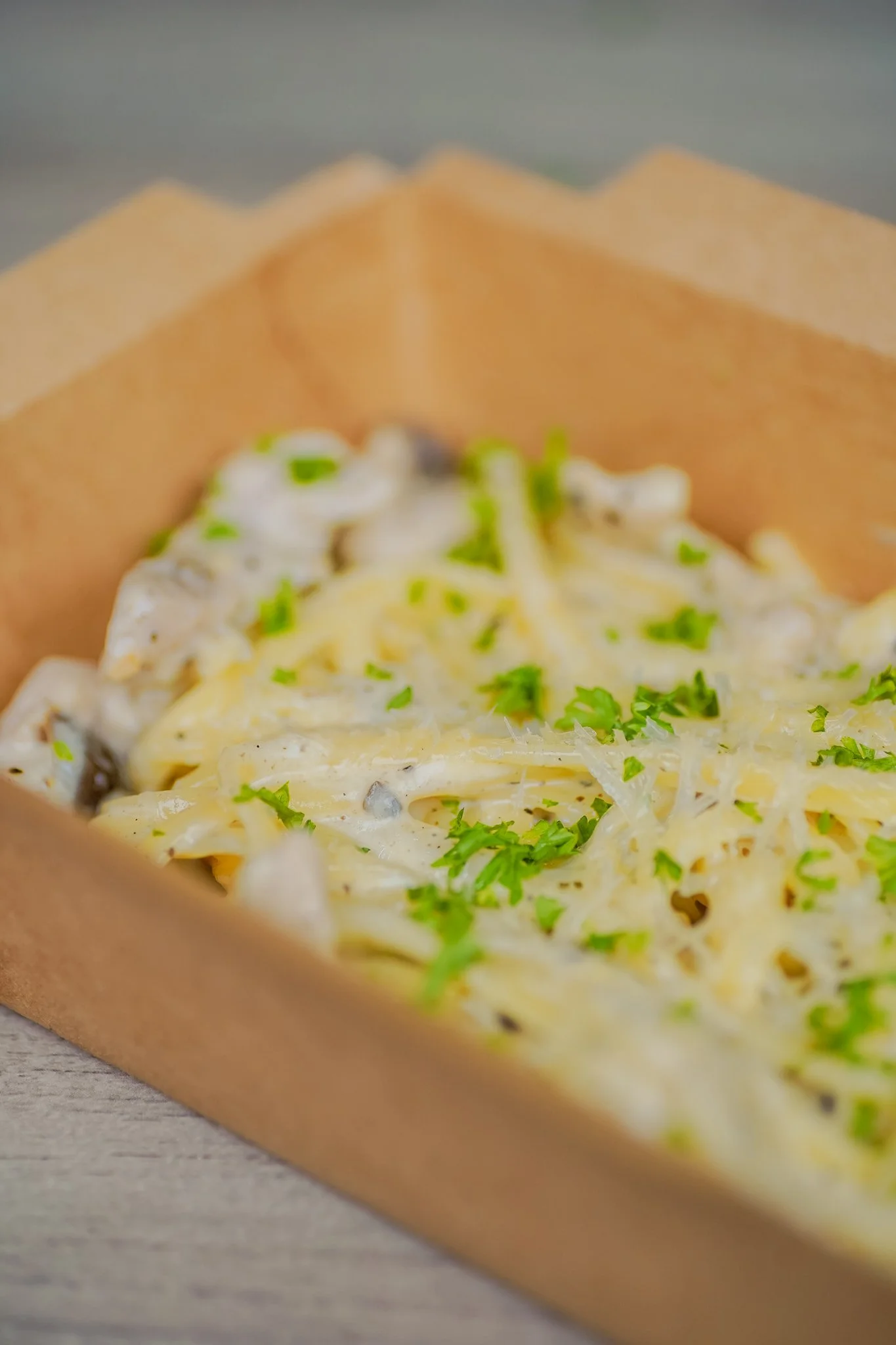 Baked creamy pasta with cheese and herbs in a paper-lined tray.