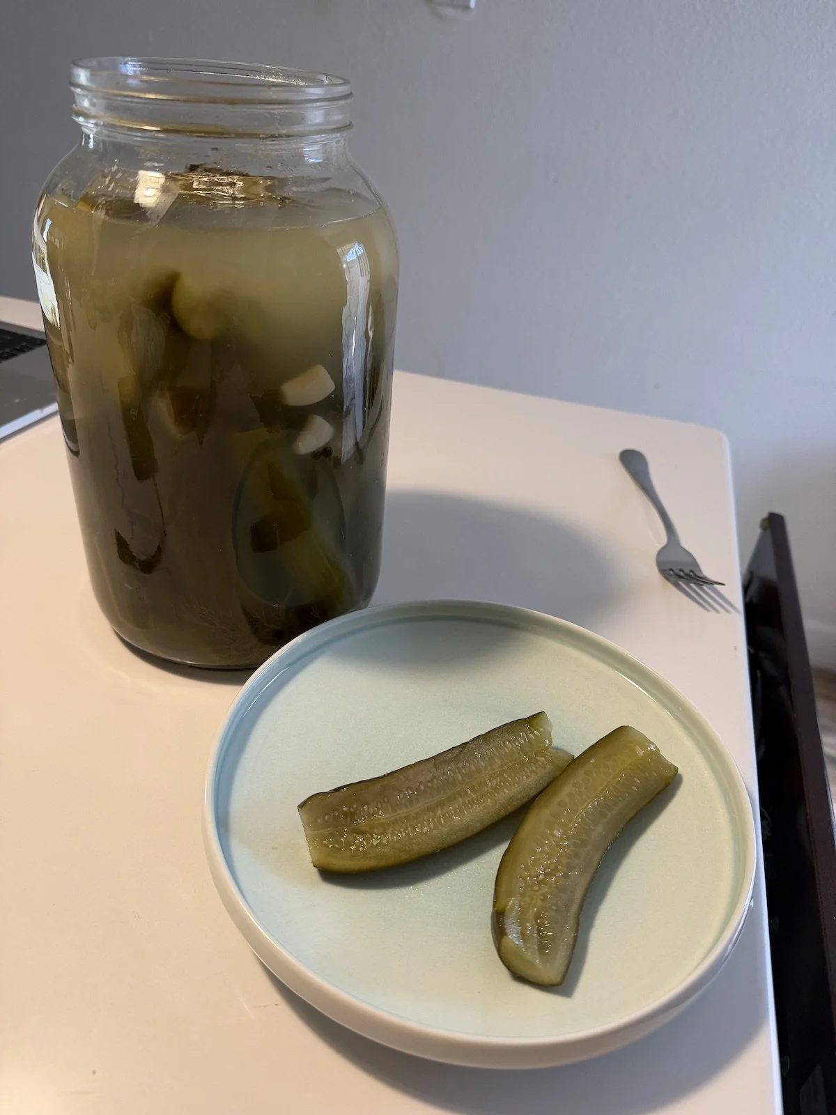 Three days later: the brine has turned cloudy, the cucumbers are olive-green and tangy, and the first spears are ready to eat.