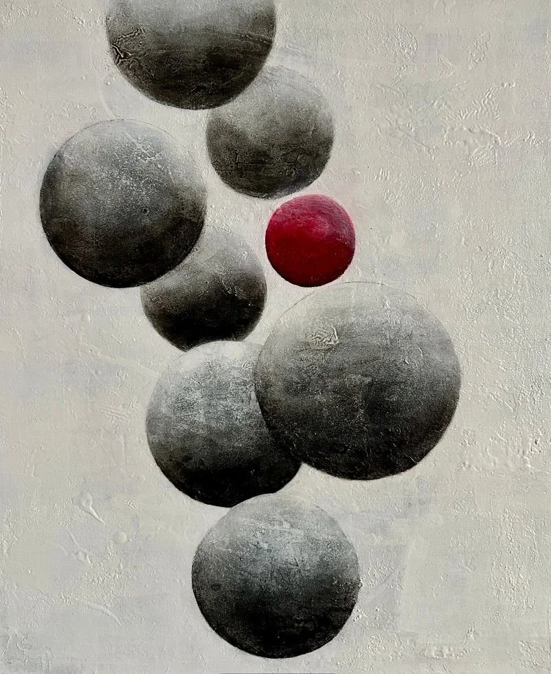 Mehrere schwarz-weiße Kugeln und eine rote Kugel, die an einer Schnur hängen, hängen gegen eine weiße Wand.