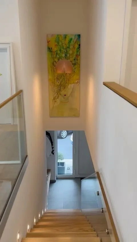 Blick vom oberen Stockwerk nach unten auf eine Treppe und eine gläserne Tür im Eingangsbereich.