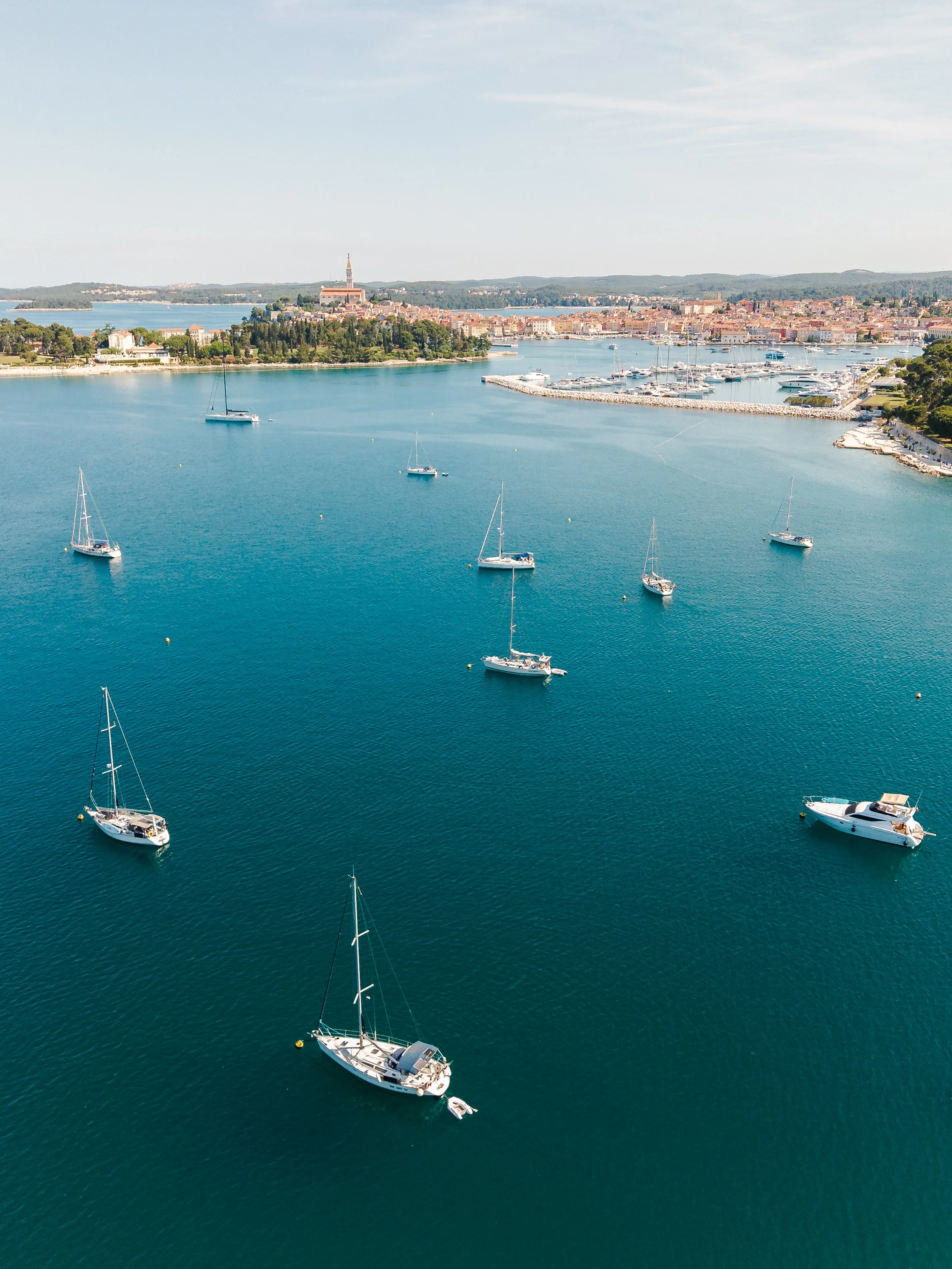 Aerial view of sailboats anchored in Rovinj near the Croatian coast - photographed by Island Media with the DJI Air 3S.