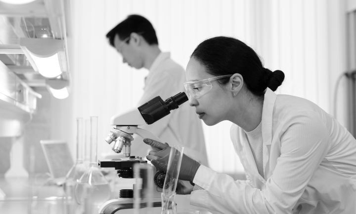 Scientist looking through a microscope in a laboratory setting.