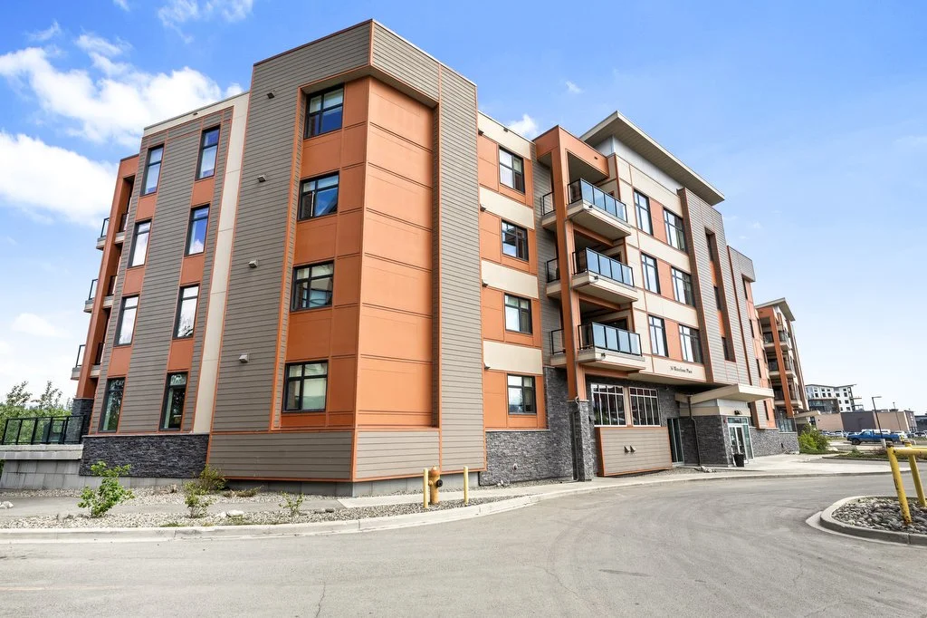 Exterior view of a modern multi-story residential apartment building with orange and beige siding, and balconies, under a blue sky.