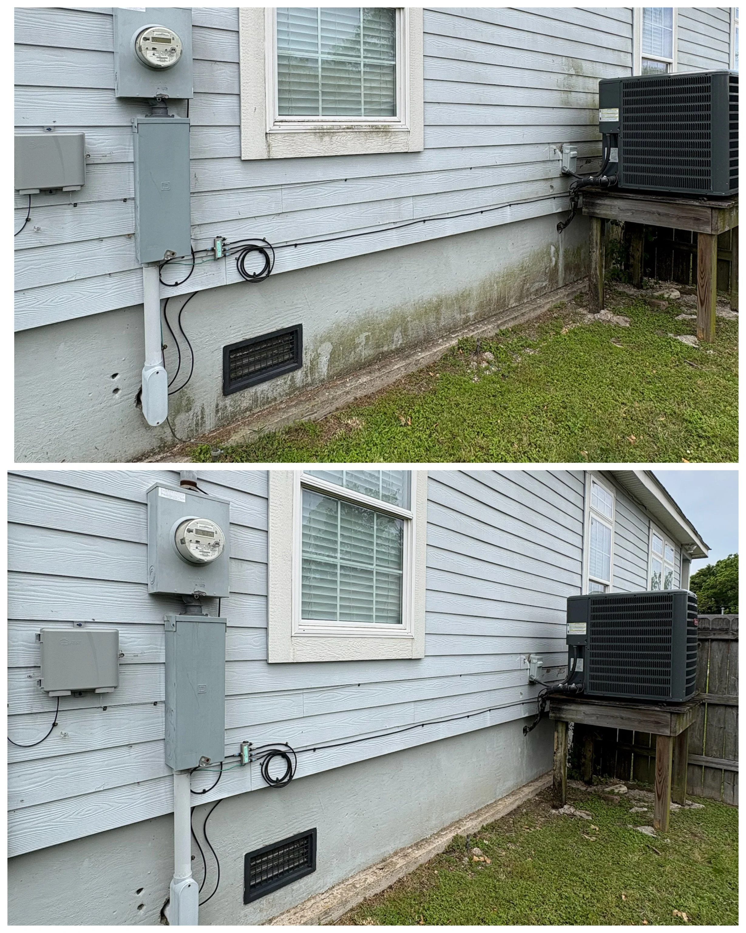 Side of a house with gray wooden siding, an electric meter, electrical boxes, and a large black HVAC unit mounted on a wooden platform. Green grass and a vent at the bottom of the house are also visible.
