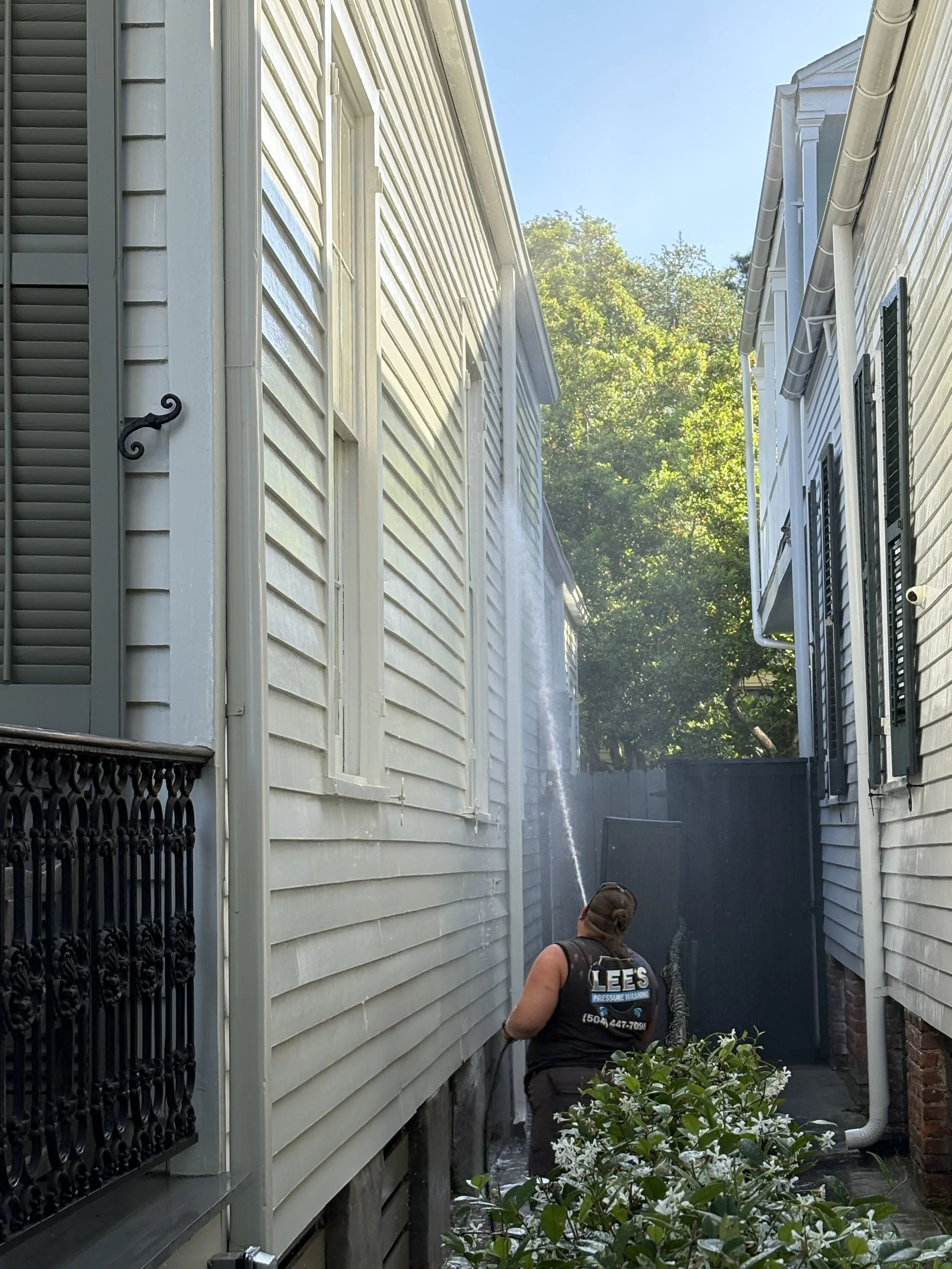 A technician soft washing a painted wood siding home in the Garden District of New Orleans, LA.