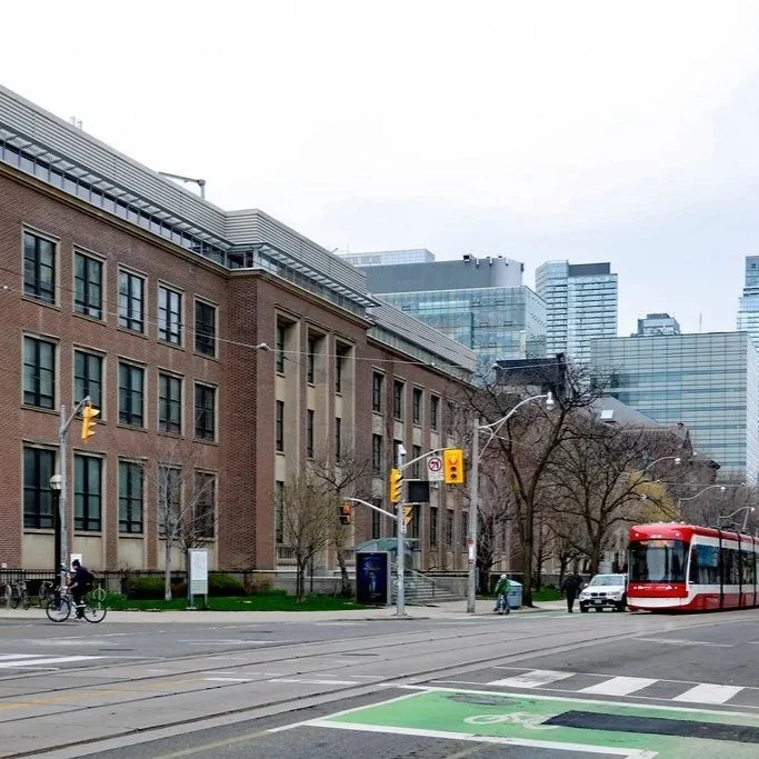 Urban street scene with a red streetcar, pedestrians, bicycles, and modern buildings in the background