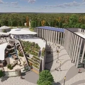 A modern outdoor shopping mall or entertainment complex with retail stores, with a large, curved building and a multi-level outdoor area featuring walkways, seating, and landscaping.