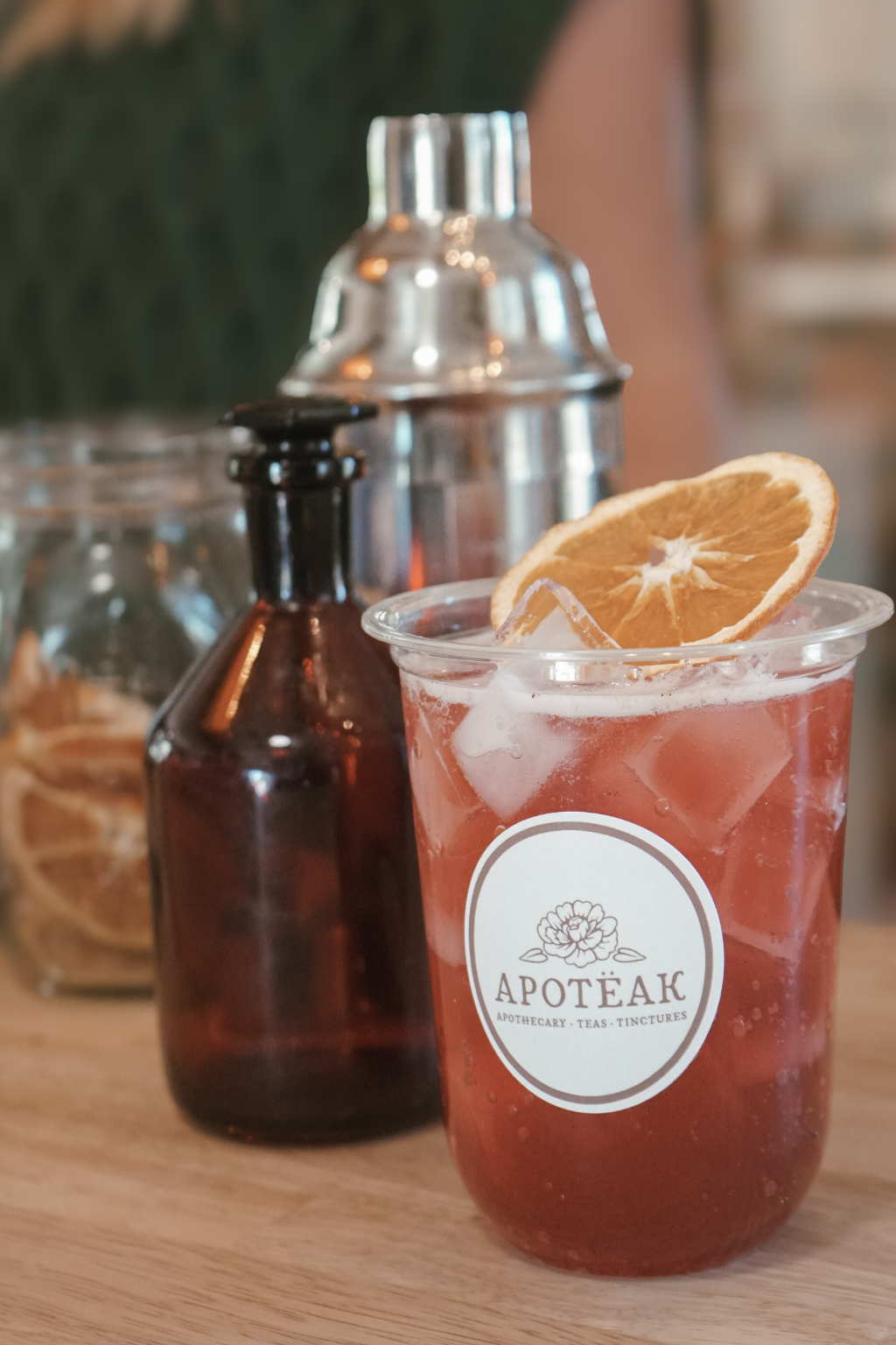 Functional wellness drink with orange slice and drink shaker in a cup with apoteak logo