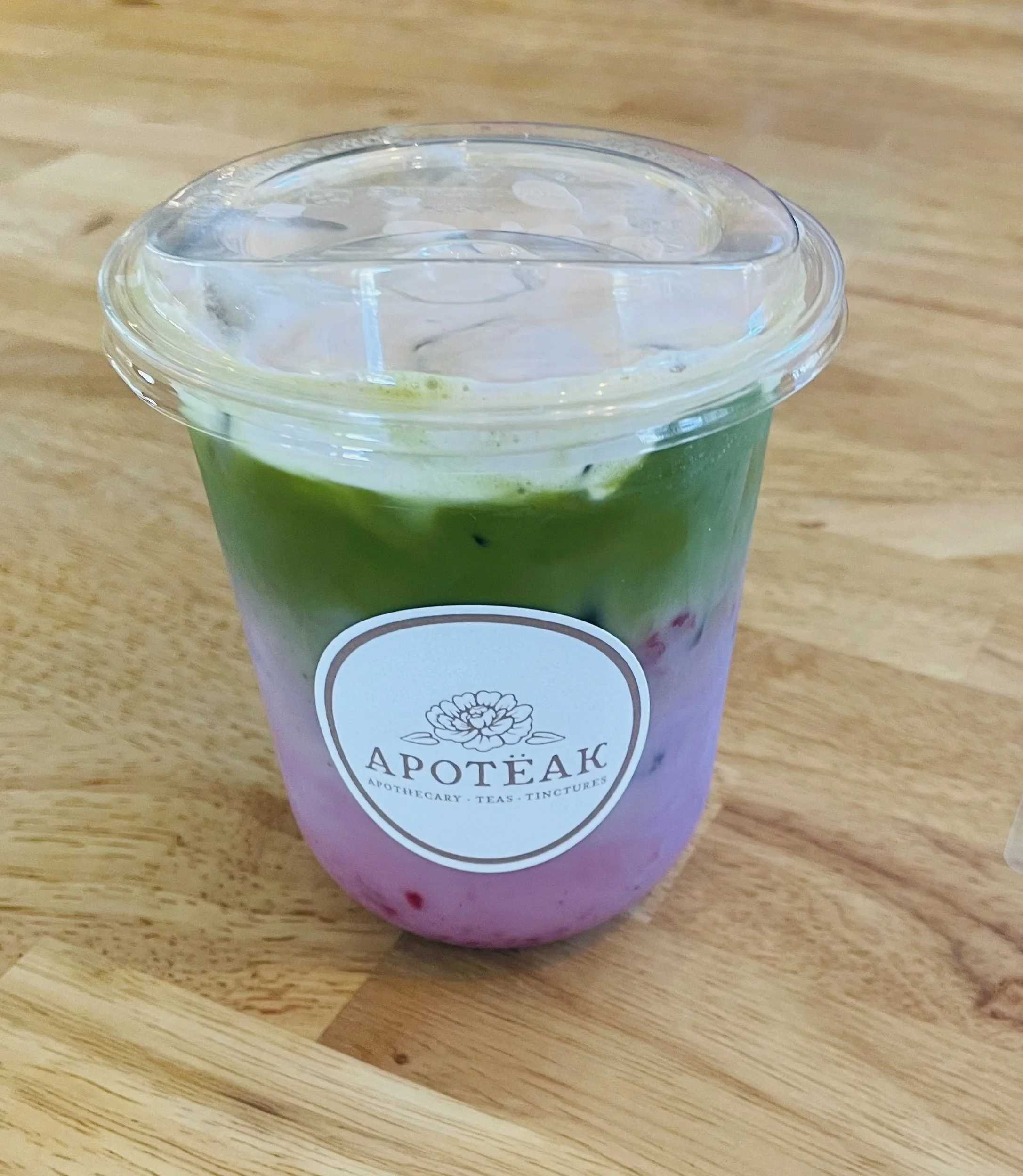 Matcha with house made oat milk with fruit puree and cold whip in Apoteak branded cup