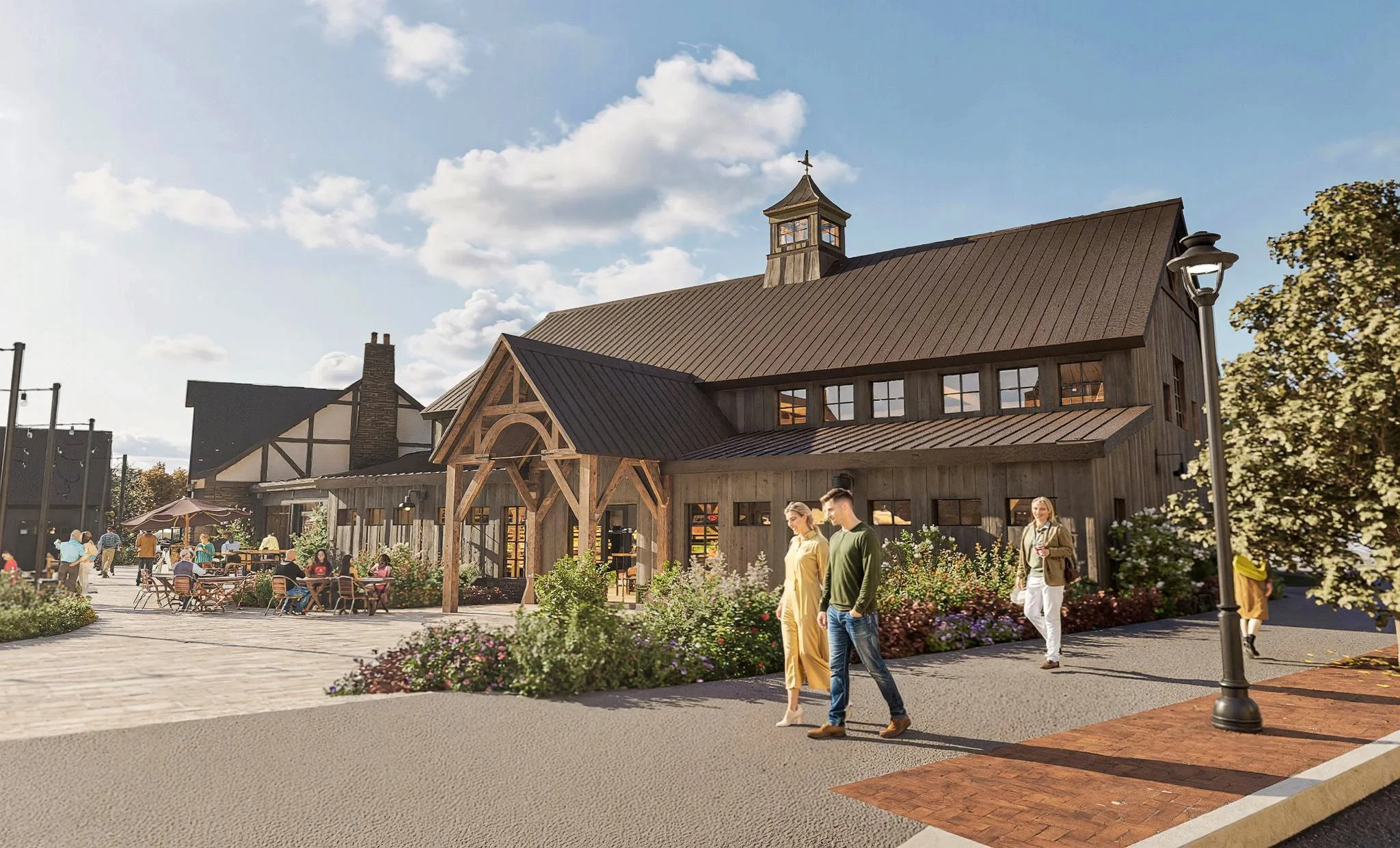 A rustic-style outdoor shopping or dining area with wooden buildings, people walking and sitting at tables, and a clear blue sky.