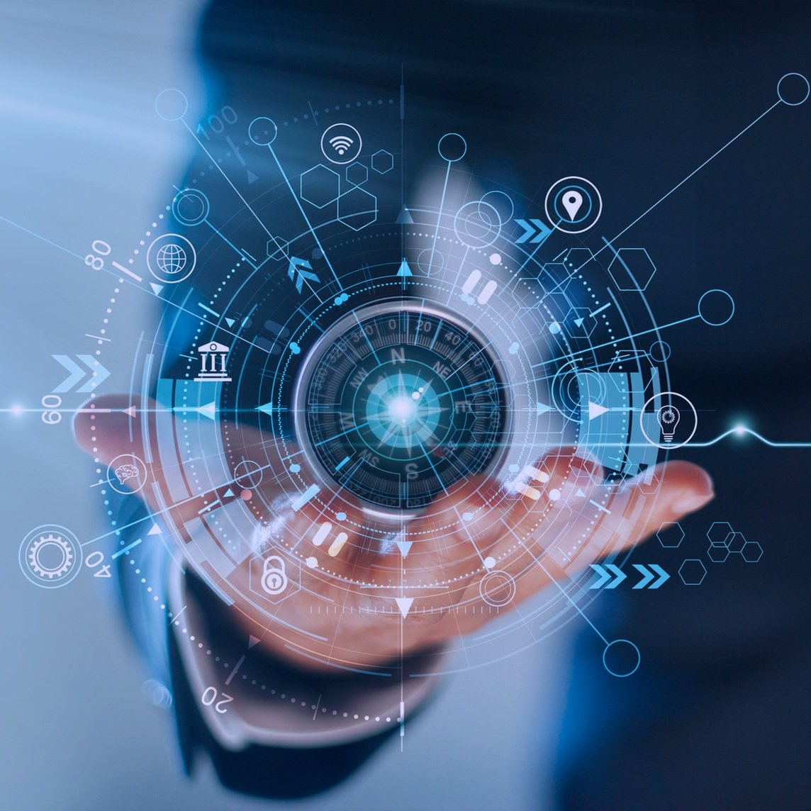 A person's hand reaching out towards a digital interface with various technological icons and data visualizations, including a compass, network symbols, and geometric shapes, glowing against a dark background. Found on BeIndigo Consulting Group site.