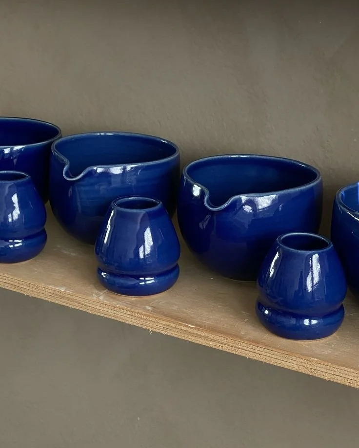 Collection of small and large blue ceramic bowls and pots on a wooden shelf.