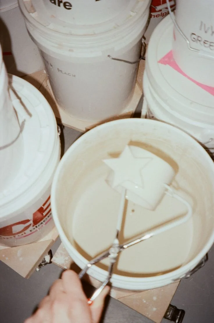 Bucket filled with white paint and a star-shaped paint roller in the bucket.