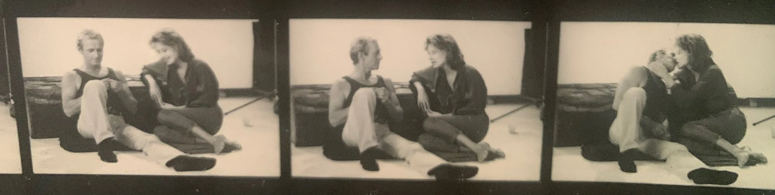Black and white strip of three photo booth images of two women sitting on the floor, one playing a guitar.