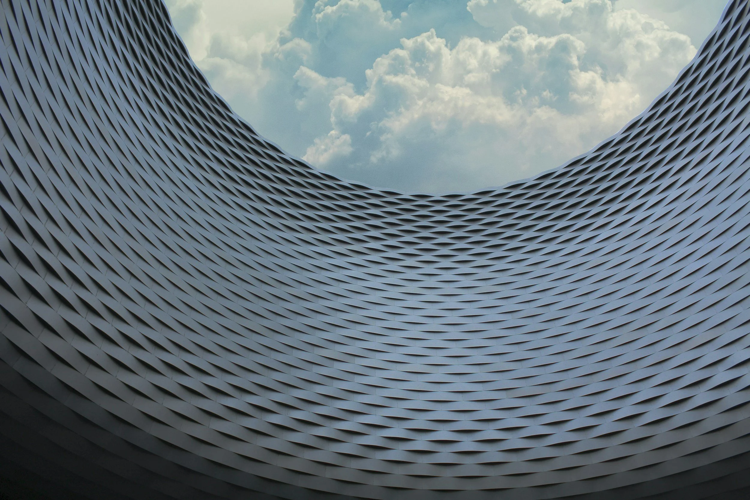 Circular building with a perspective standing in the center, looking up toward the sky, framed by the building’s curved walls.