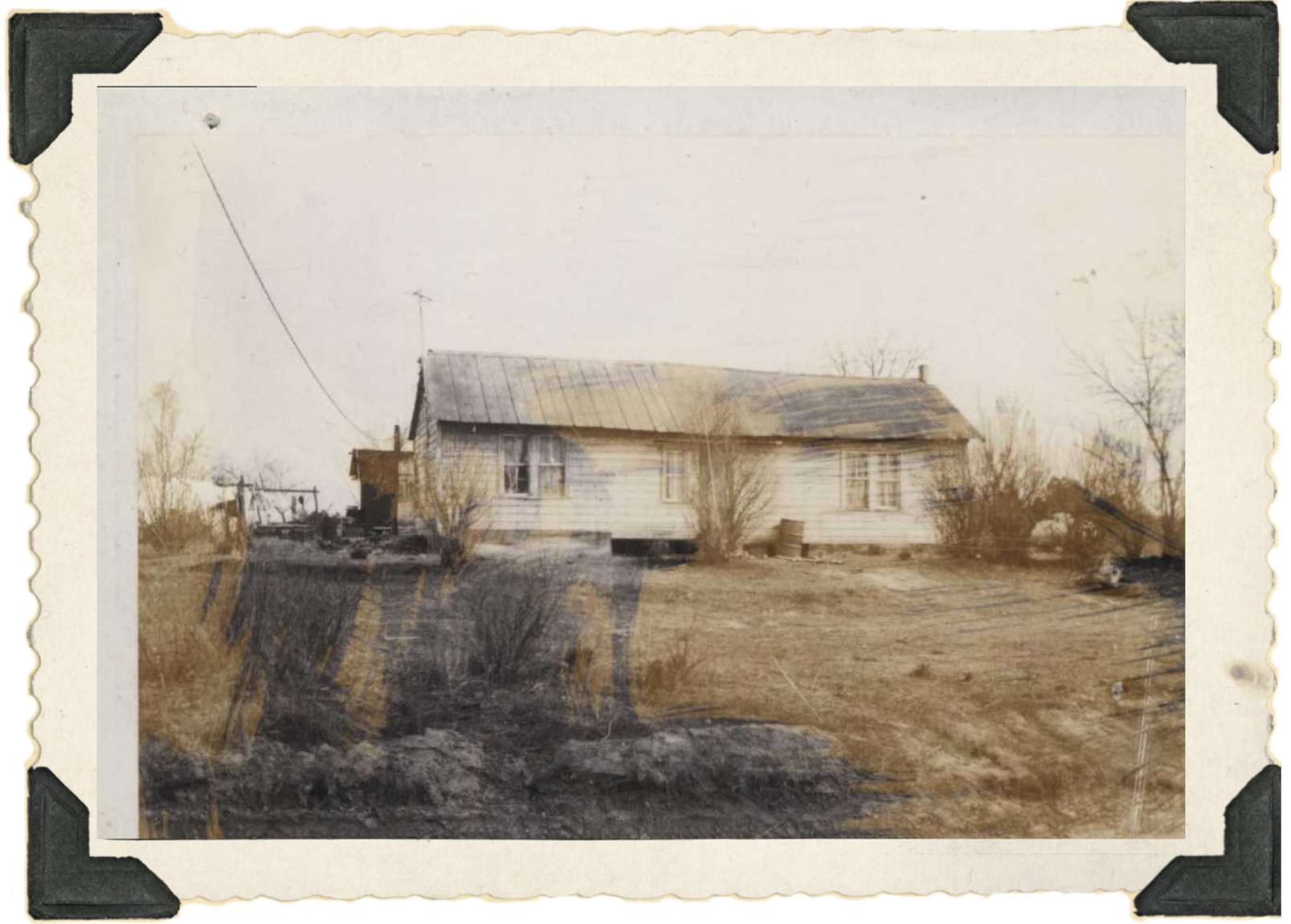 OG Hollowell House: A vintage black and white photo of a small, single story house with three windows and shrubs. The photo is yellowing with age.