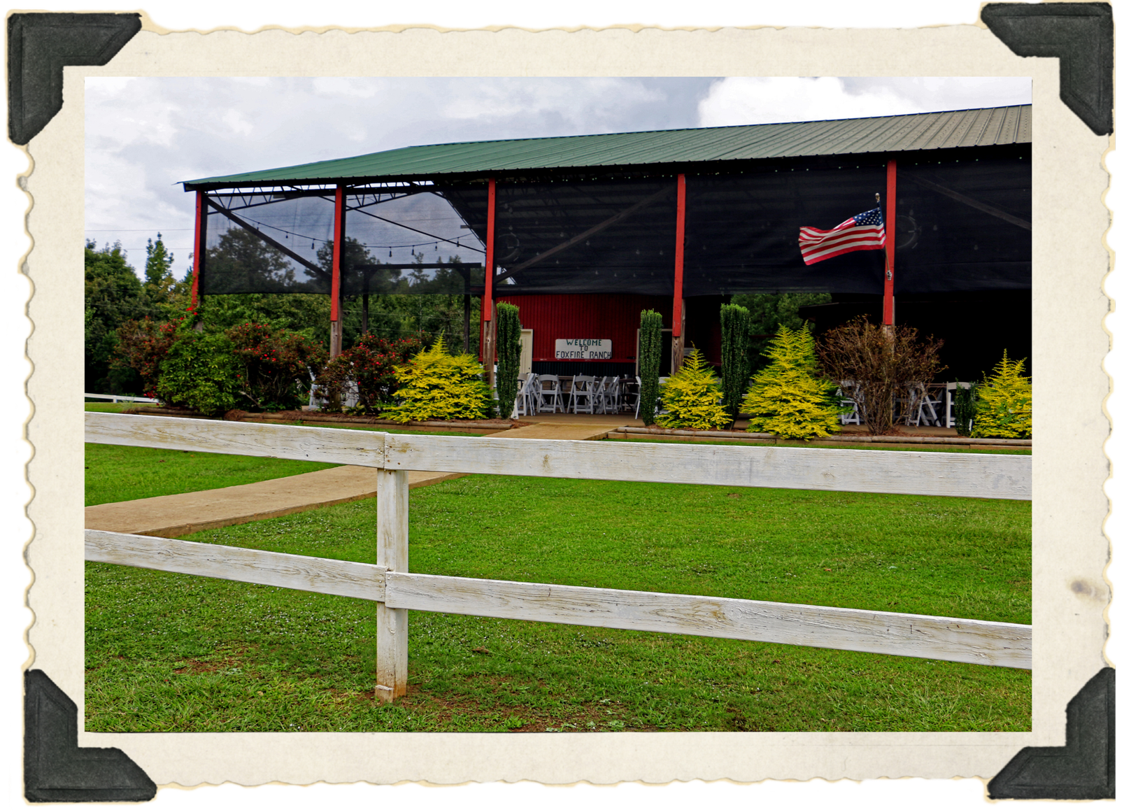 The pavillion at Foxfire Ranch in springtime. The structure has a green tin roof, and wood posts with red trim.