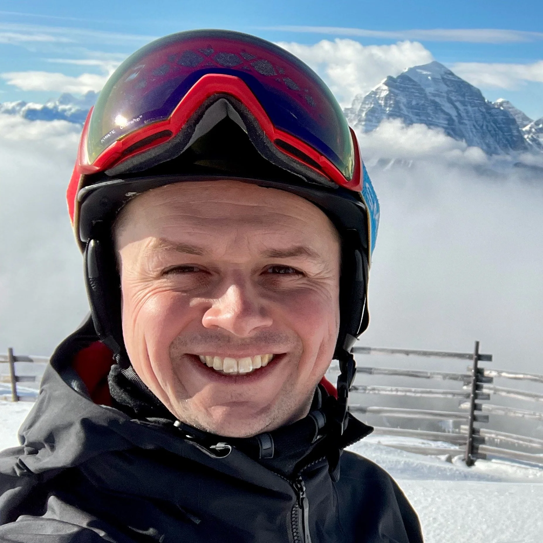 Dan Harmon wearing ski gear on a mountain top.