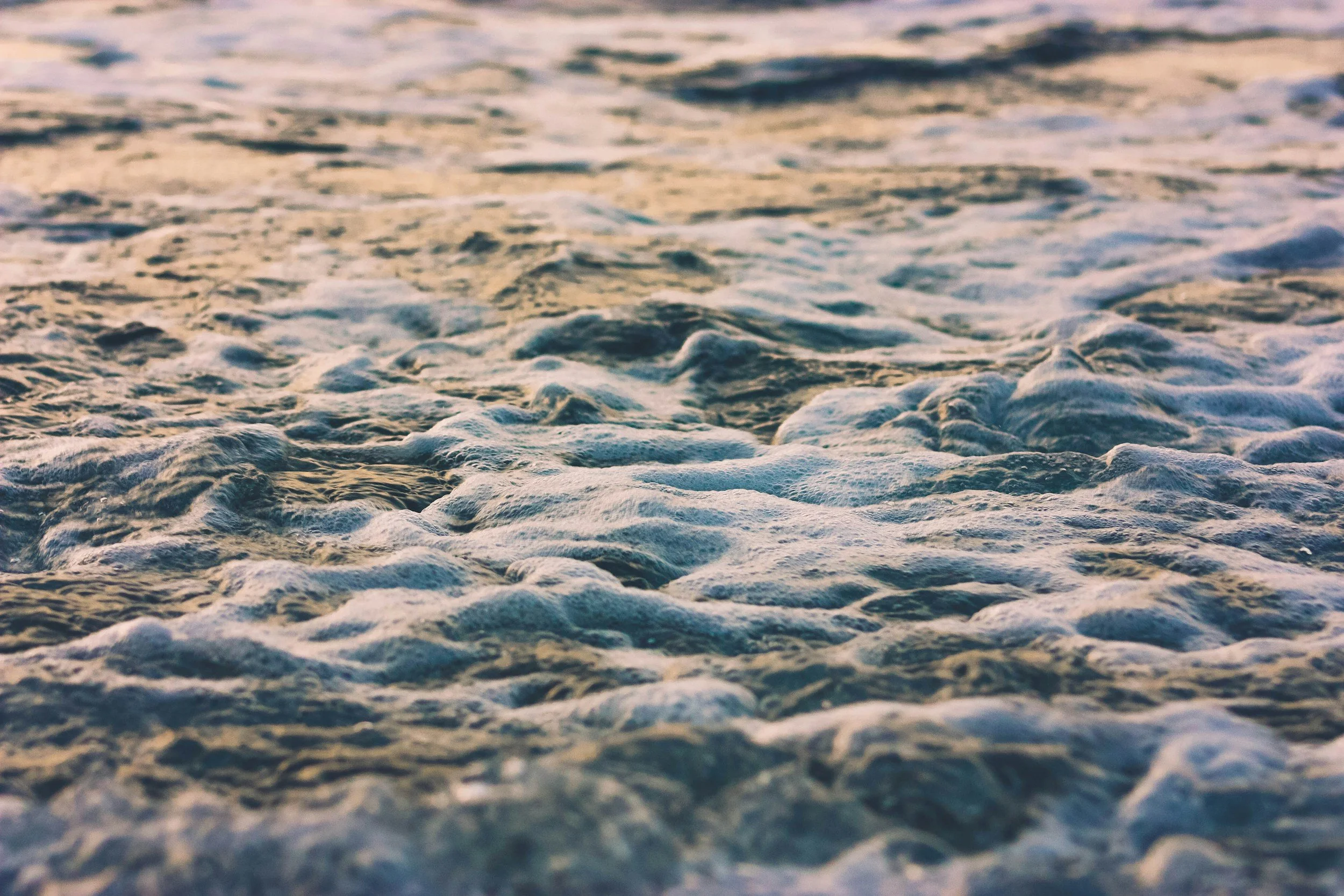 Close-up of ocean waves with foam and ripples, taken from a low angle.
