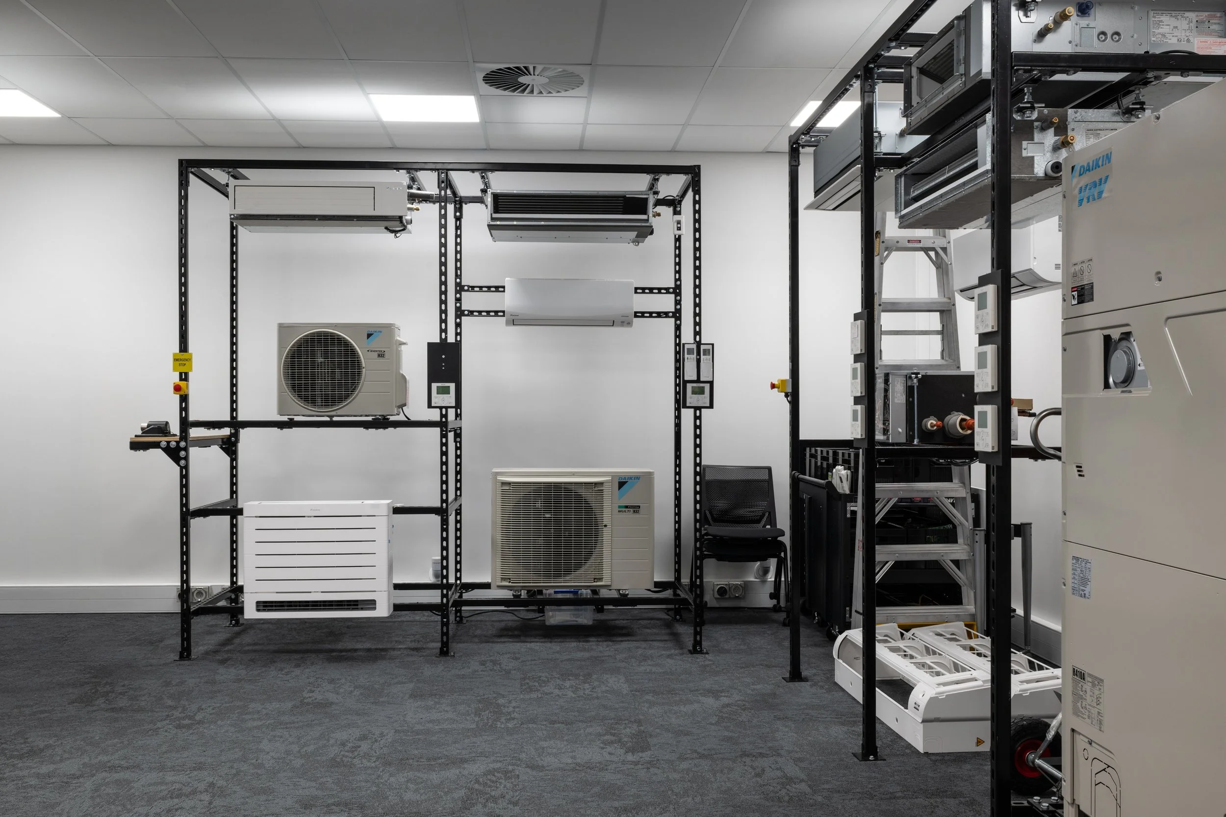 An indoor data center or server room with air conditioning units and server equipment mounted on black metal racks.