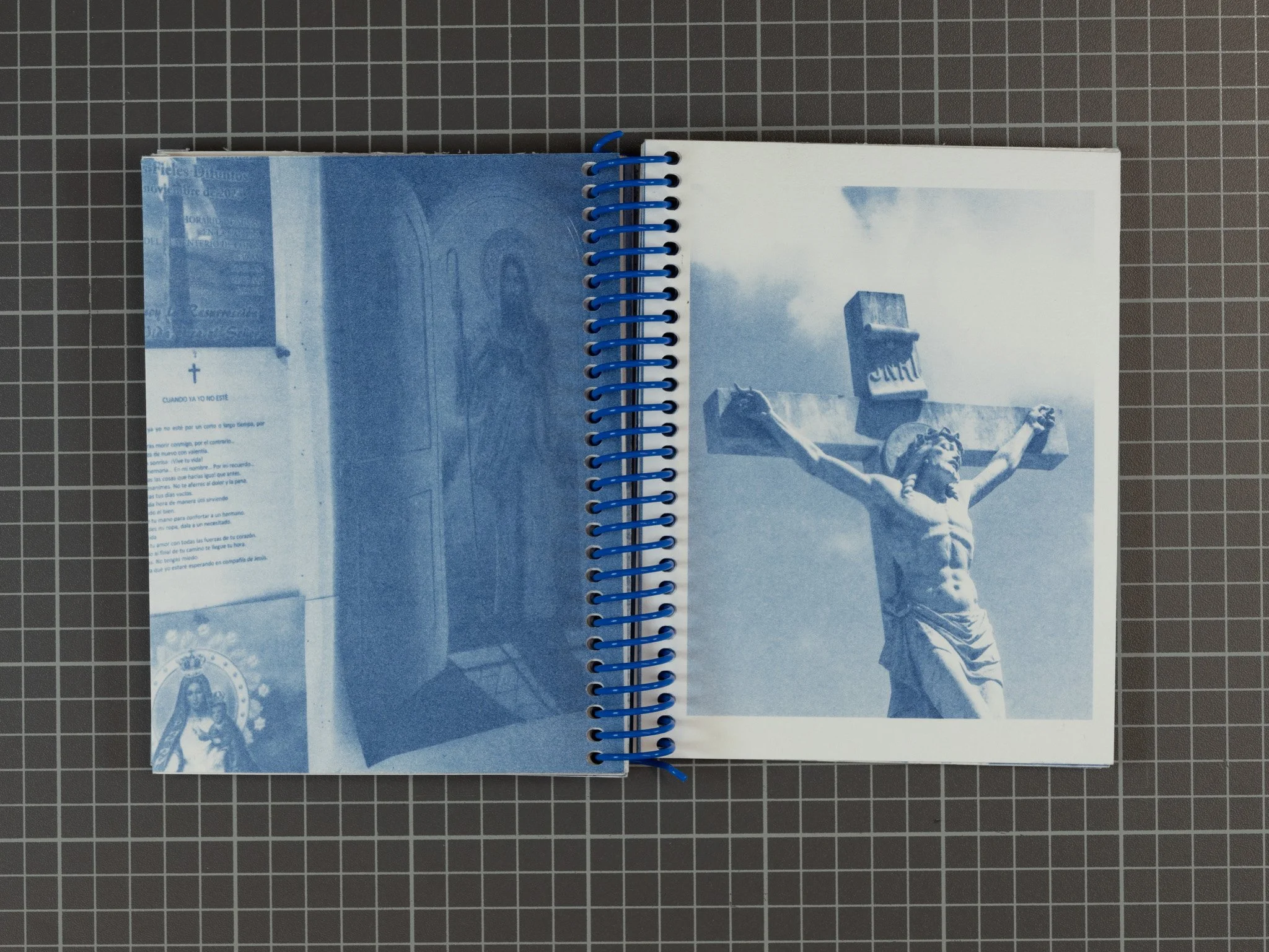 Open spiral notebook with monochrome photo of Jesus Christ on the cross on the right page and religious text on the left page, against a grid background.