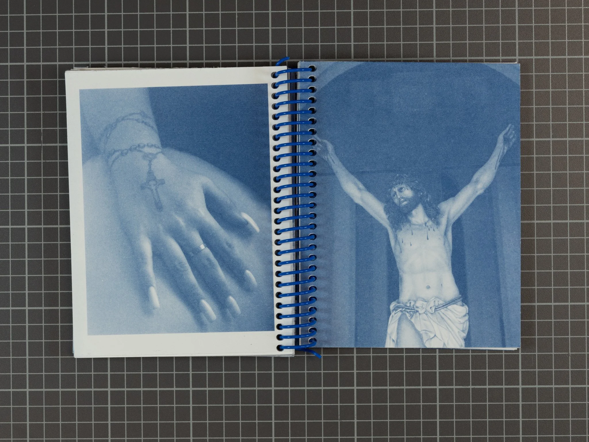 Open photo book with two images of crucifixion scenes, one shows a close-up of a hand with a cross ring, the other shows a full-length image of Jesus on the cross.