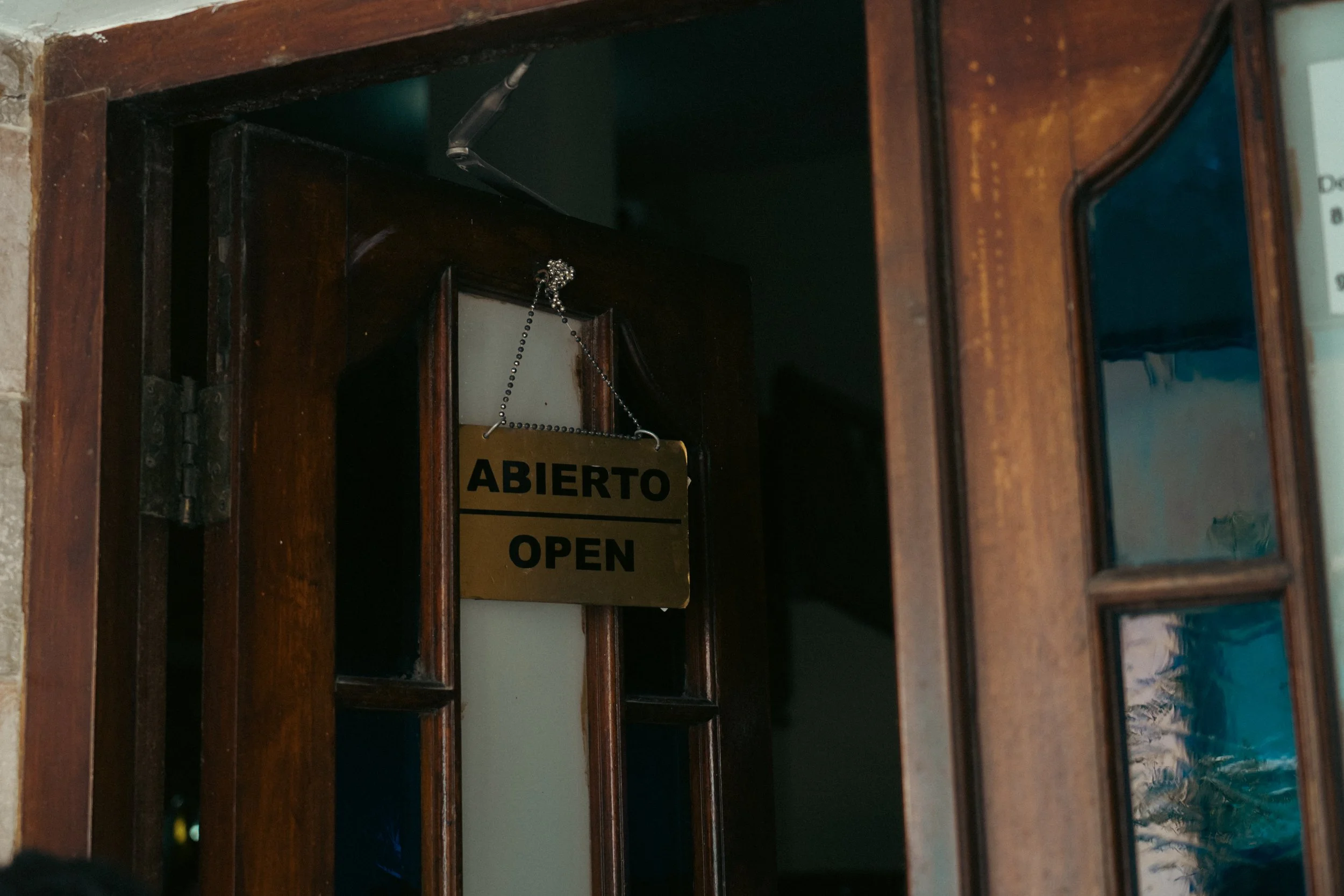 Wooden door with a hanging sign that says 'ABIERTO' and 'OPEN', indicating the place is open.
