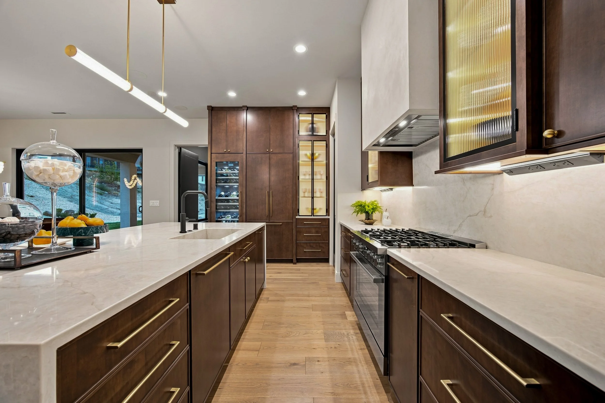 Kitchen with natural wood cabinetry, pale counters, and a sculptural range hood.