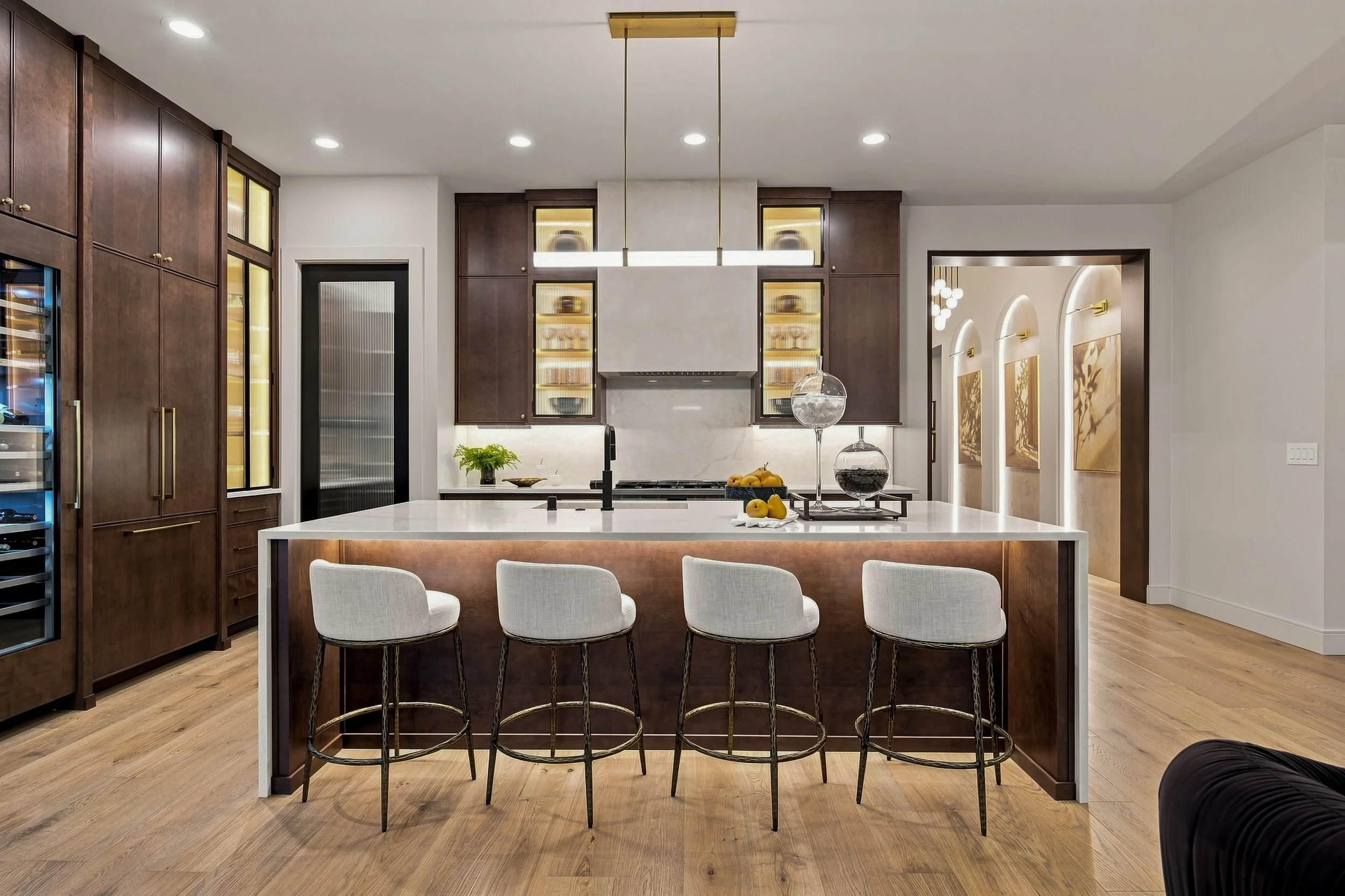 Kitchen island with upholstered stools, wood cabinetry, and pendant lighting.