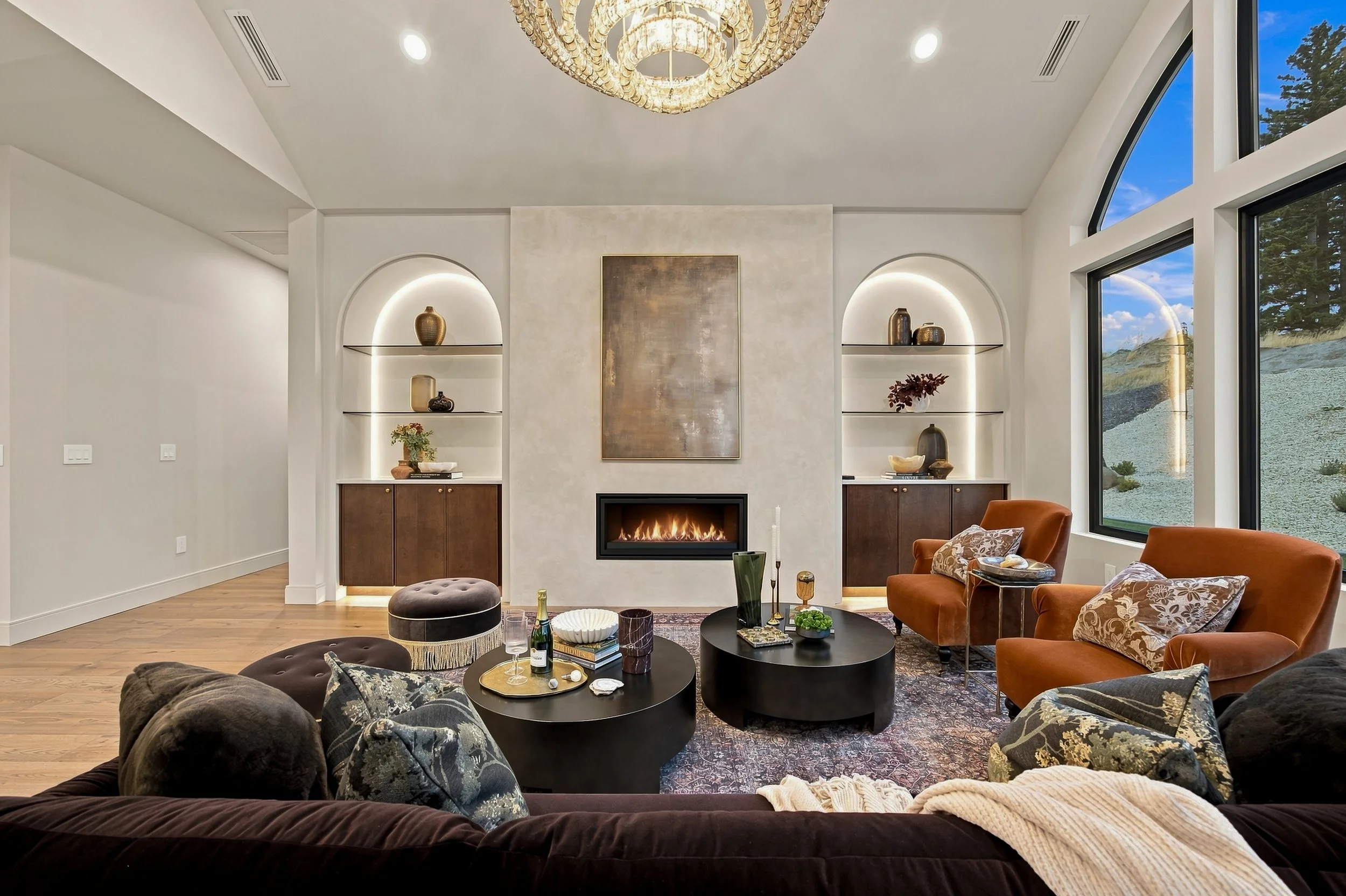 Living room with a fireplace framed by illuminated arched shelves.