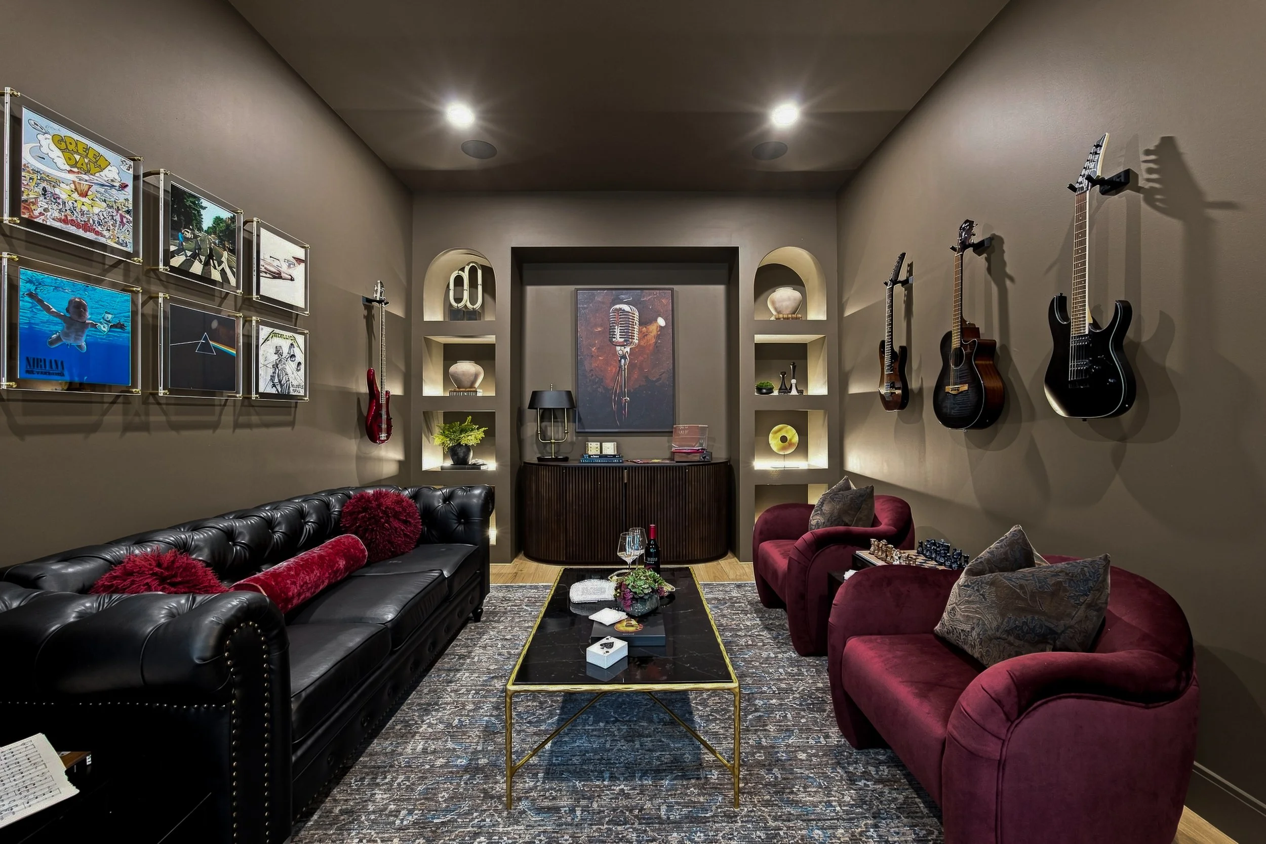 Color-drenched flex room with illuminated arched shelves, artwork, and deep red seating.