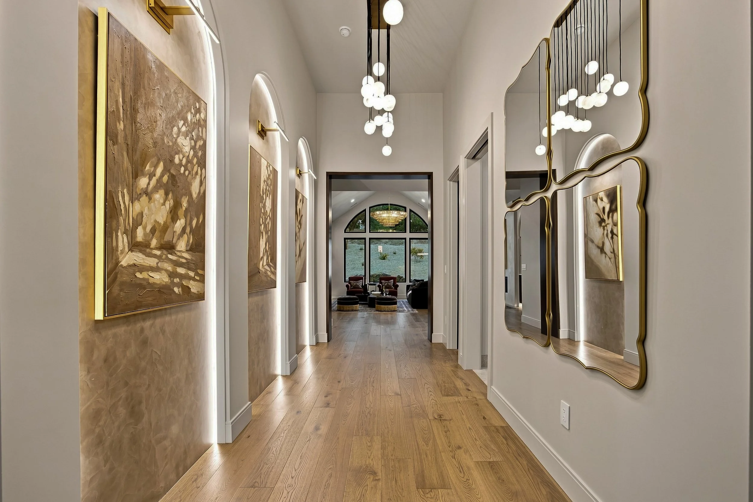 Foyer with sculpted arches, picture lights, and warm wood flooring.