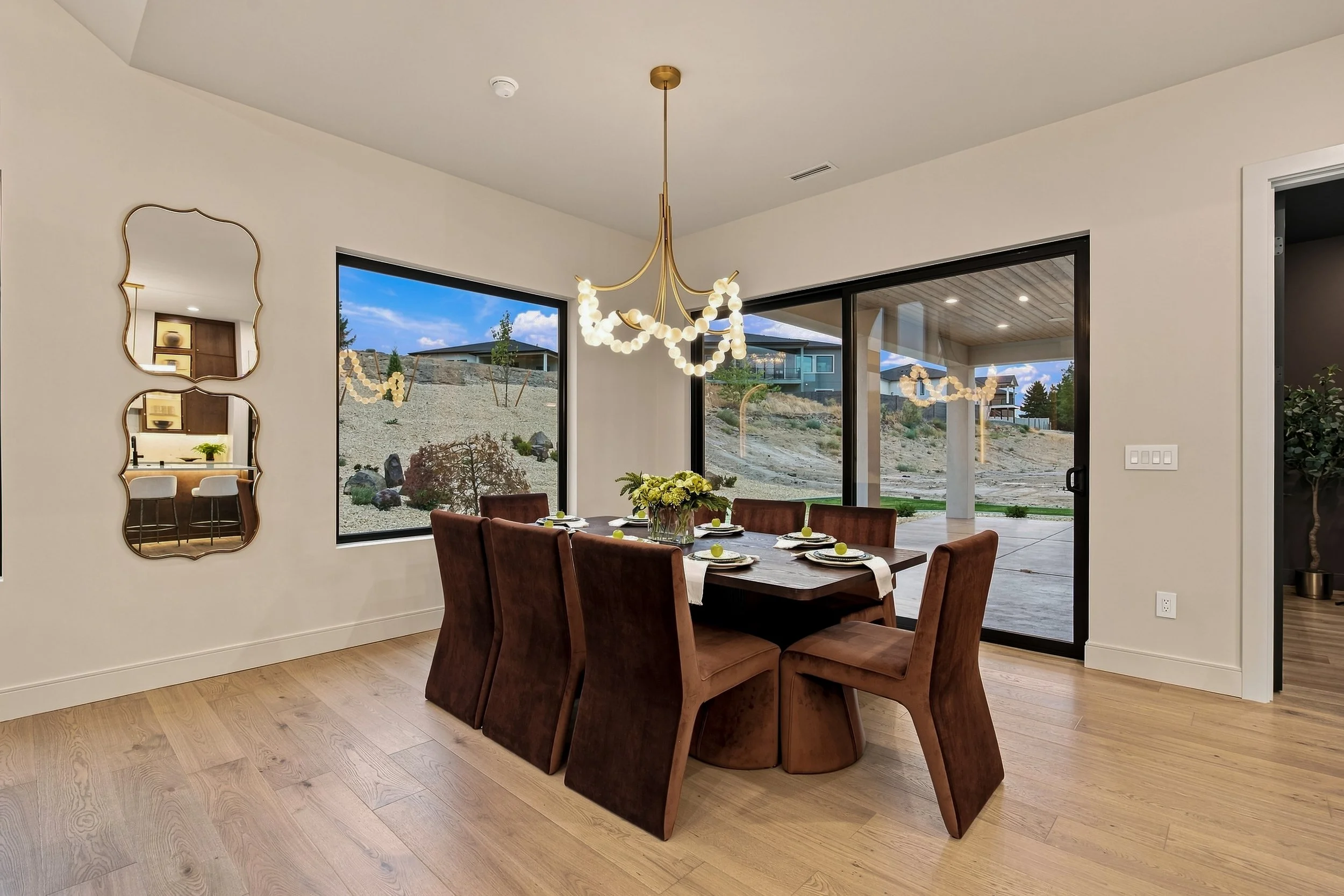 Dining room with a sculptural chandelier, upholstered seating, and large windows.