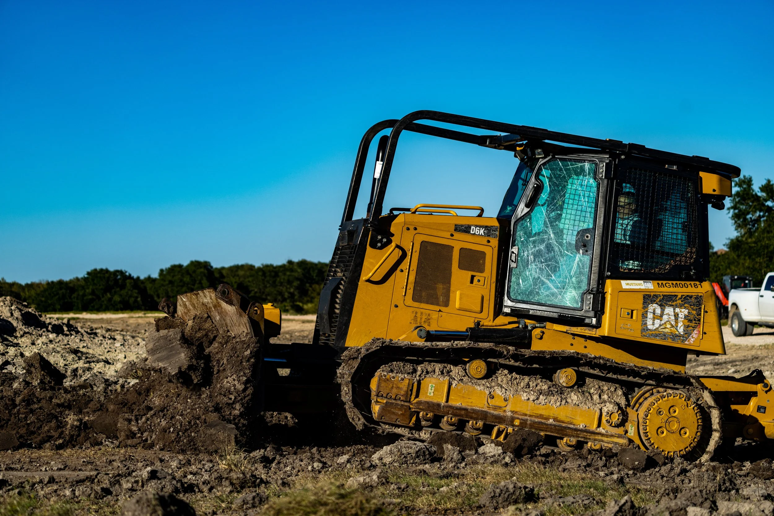 Yellow bulldozer moving dirt on a construction site with a blue sky background.