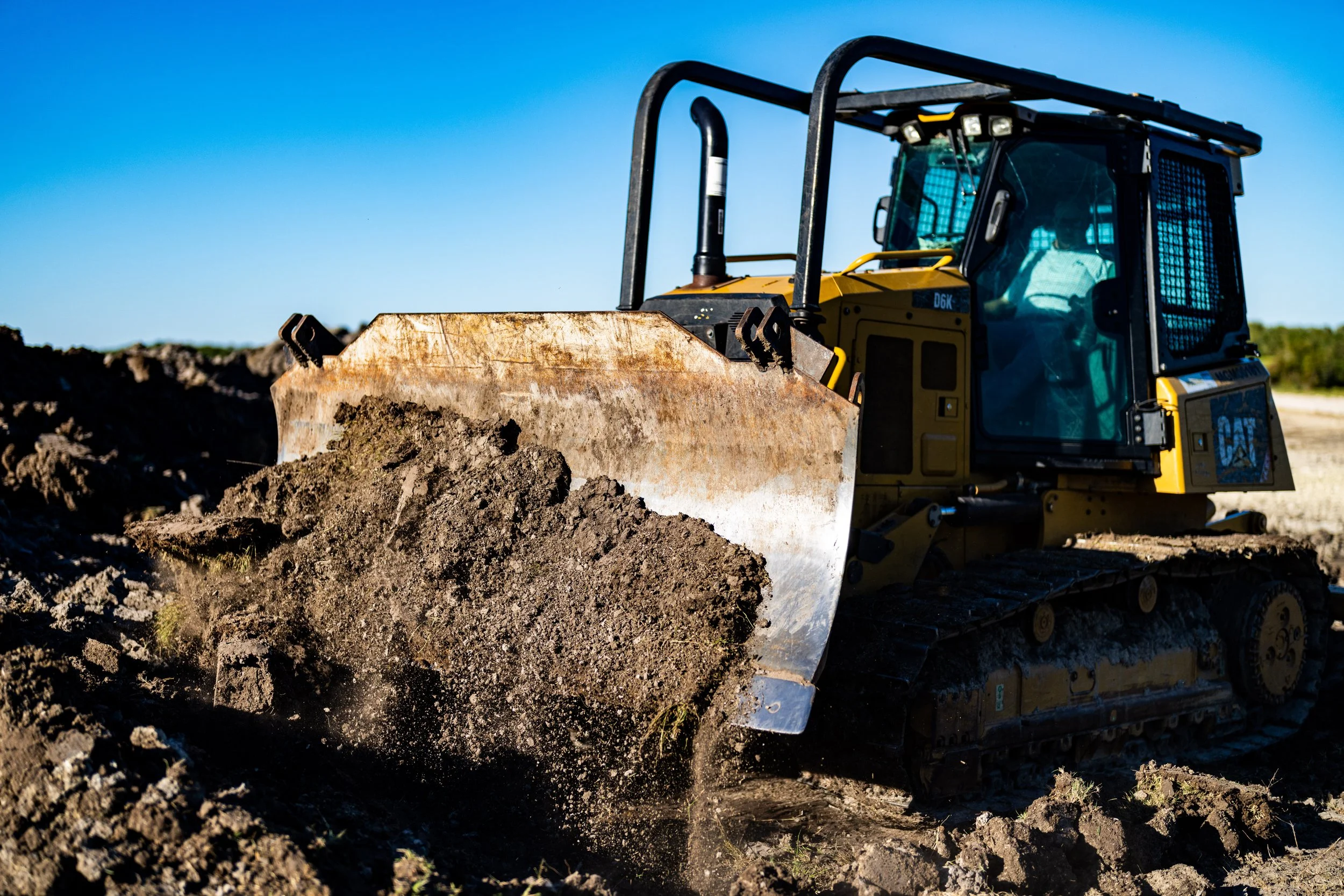 Bulldozer moving soil on construction site under clear blue sky