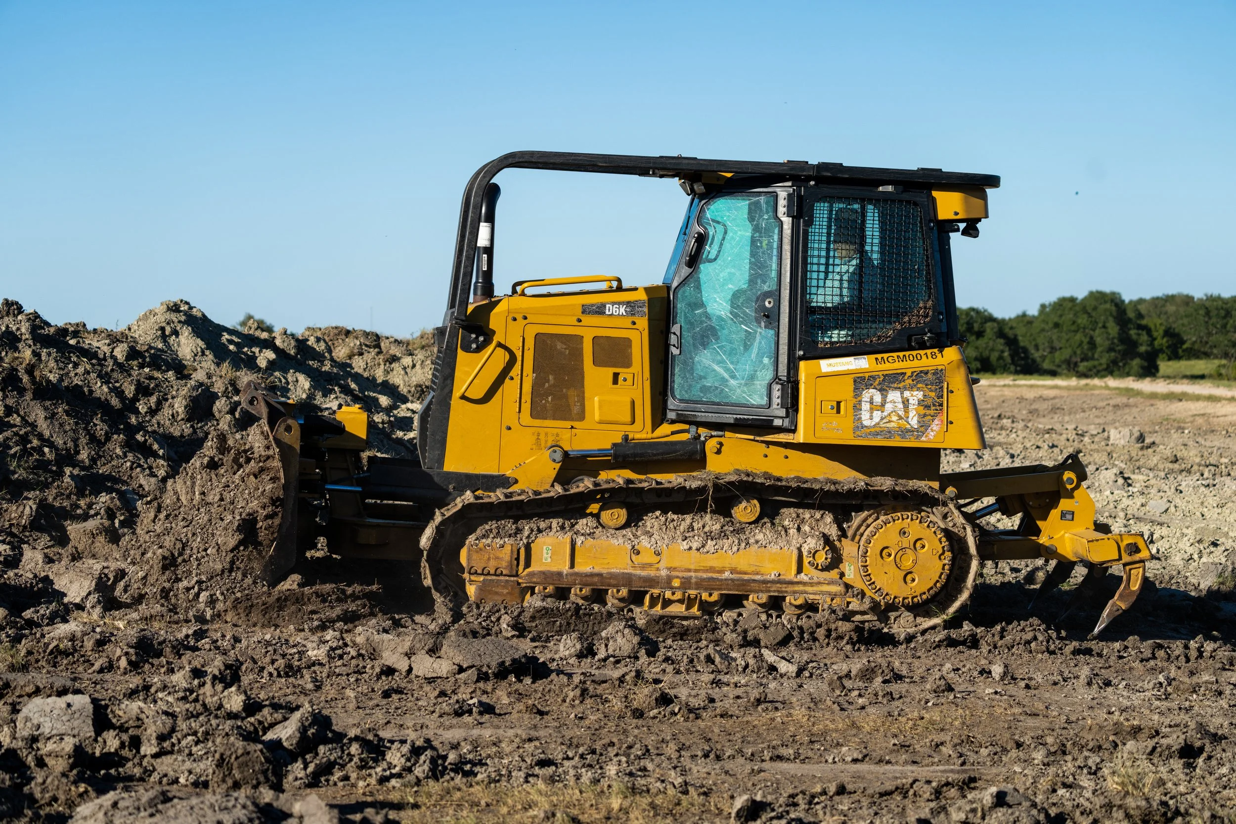 Yellow bulldozer moving dirt on a construction site under a clear blue sky.