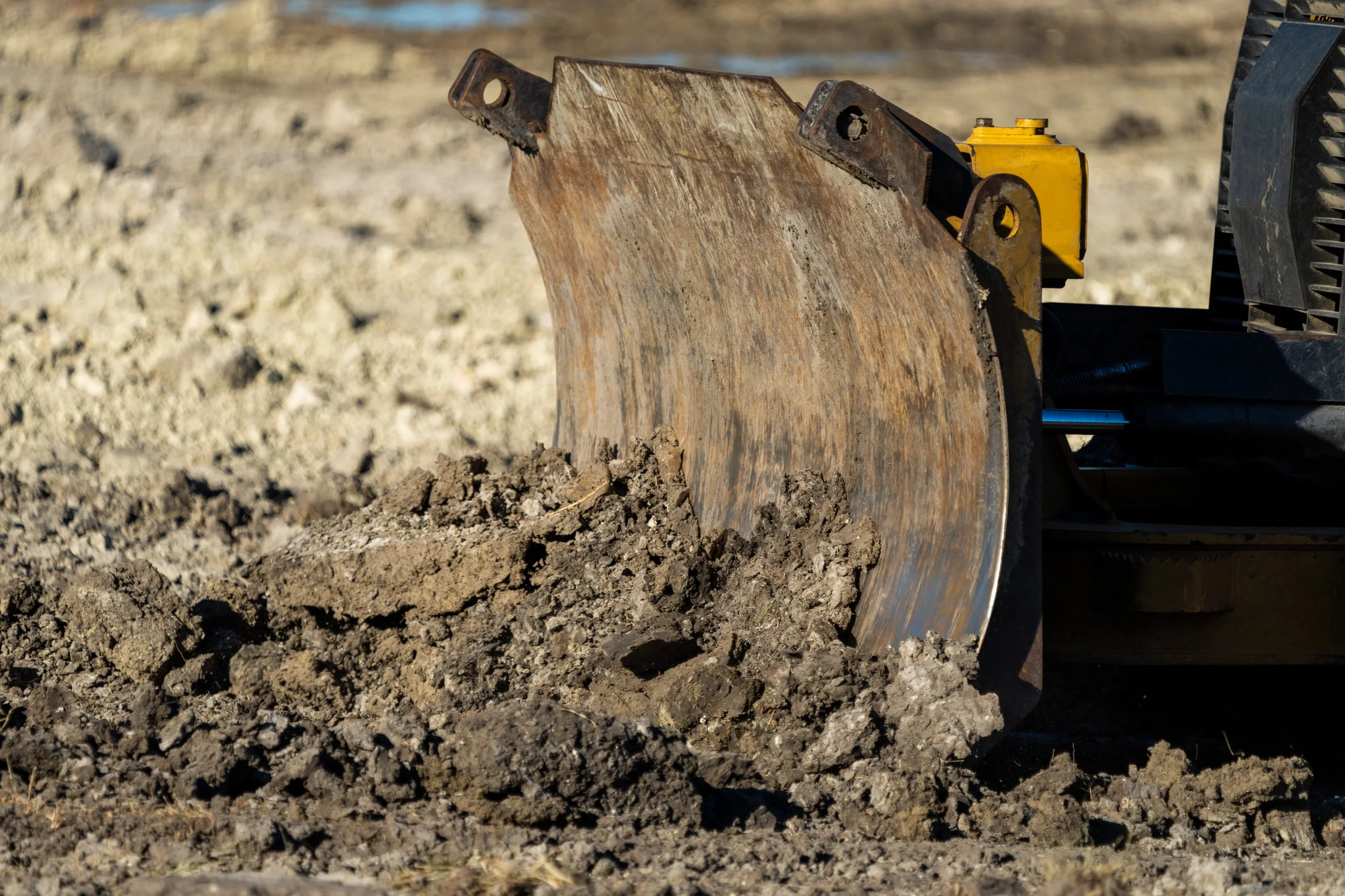 Bulldozer blade pushing dirt in a construction area.