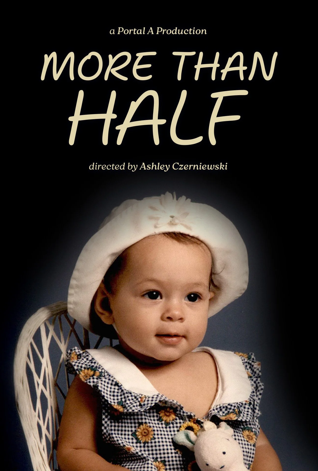 Cover of a book titled 'More Than Half,' directed by Ashley Czerniewski, featuring a young baby girl with light brown hair, wearing a white hat and a gingham dress with sunflower patterns, sitting in a white wicker chair against a dark background.