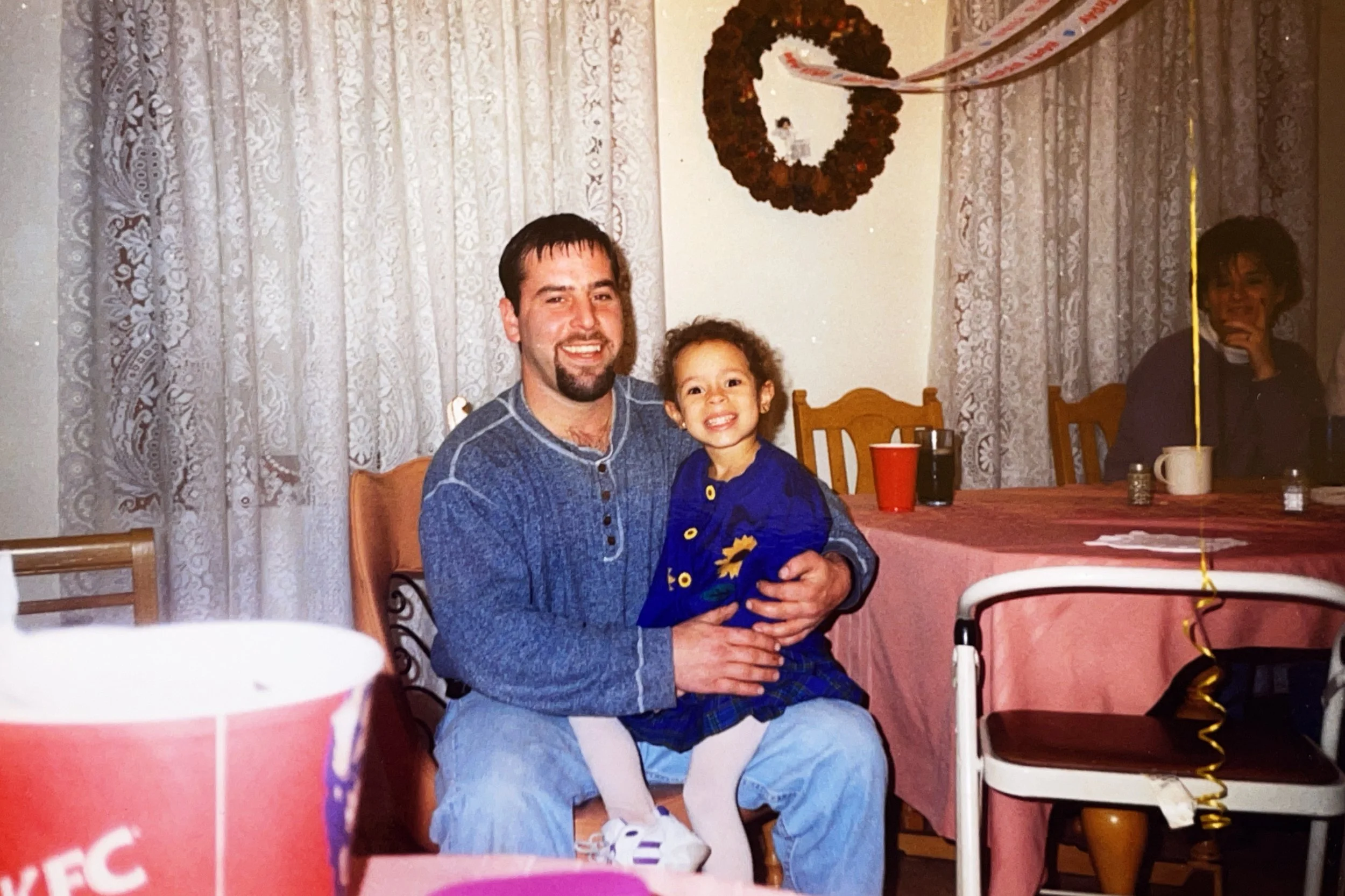 A man and a young girl smiling and sitting together at a holiday gathering