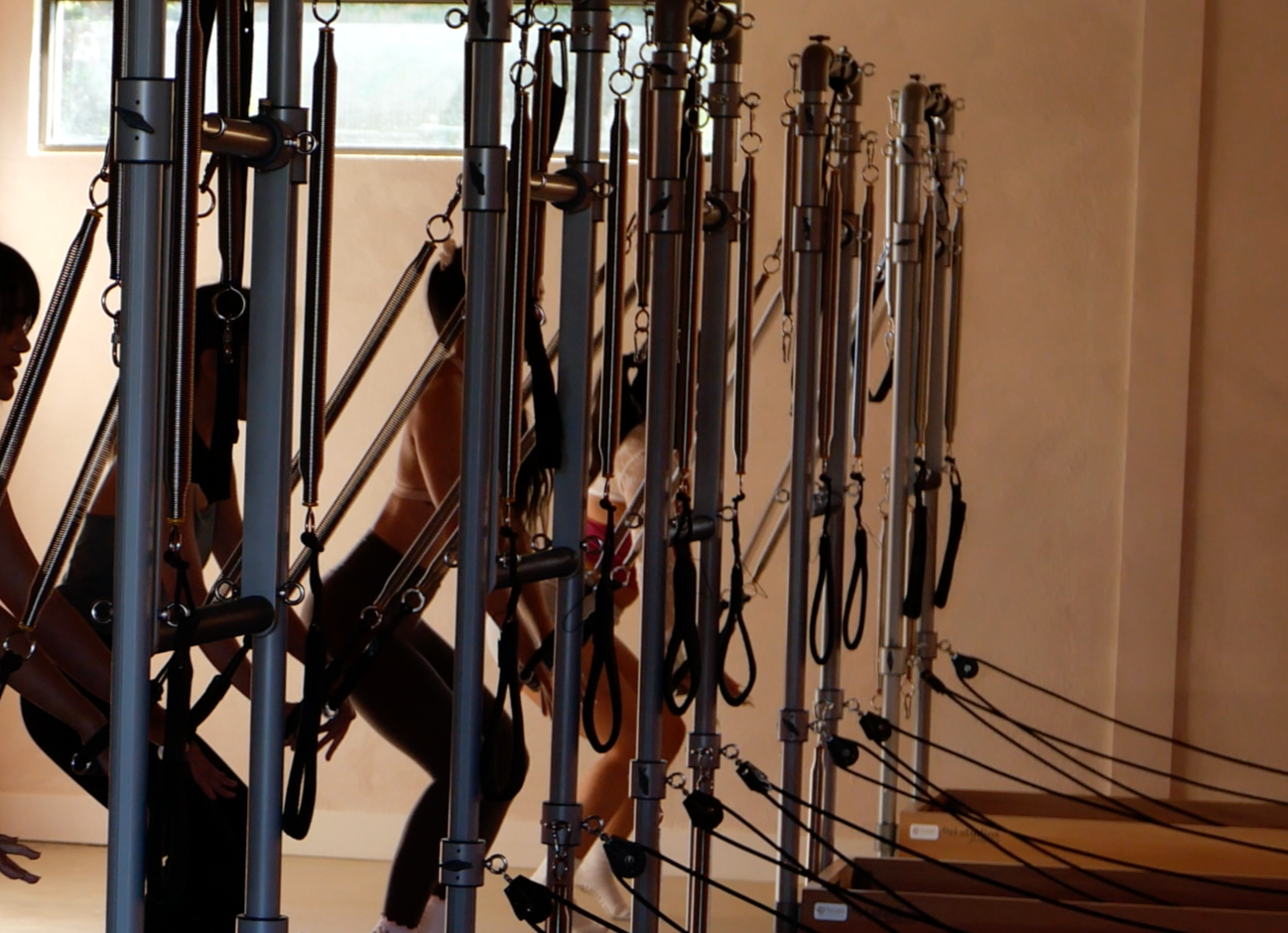 Group reformer Pilates class at Ori Studios with members moving through a full-body workout.