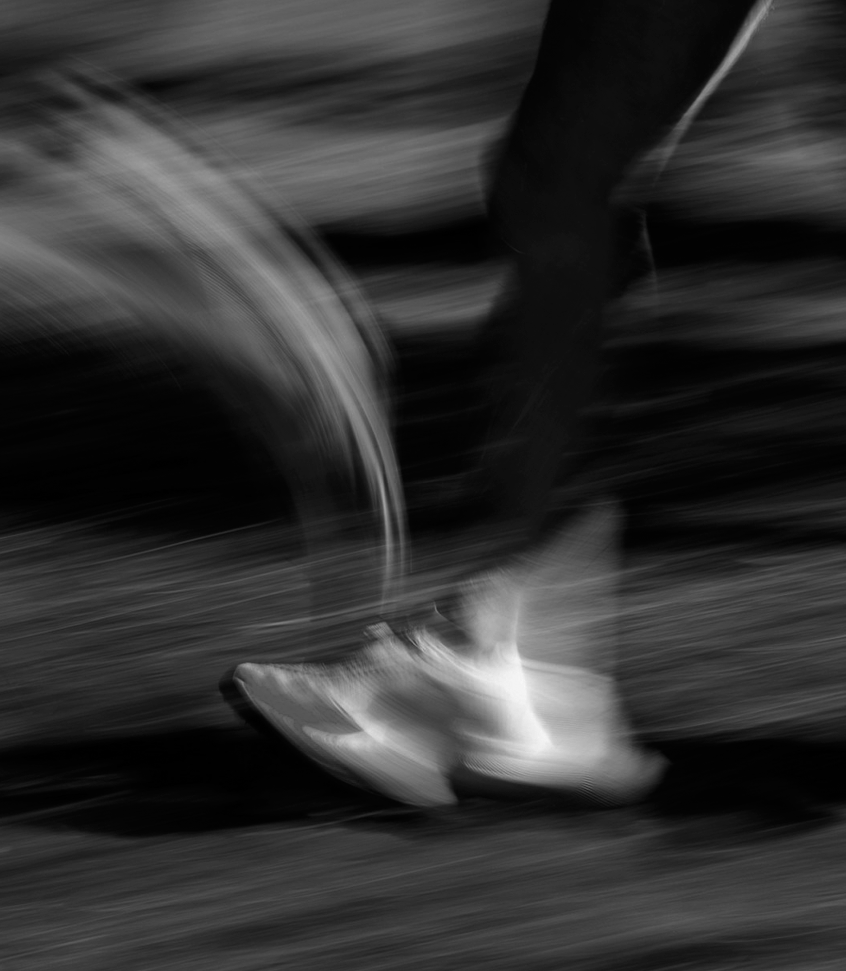 Close-up of a person running on a treadmill with motion blur in black and white.