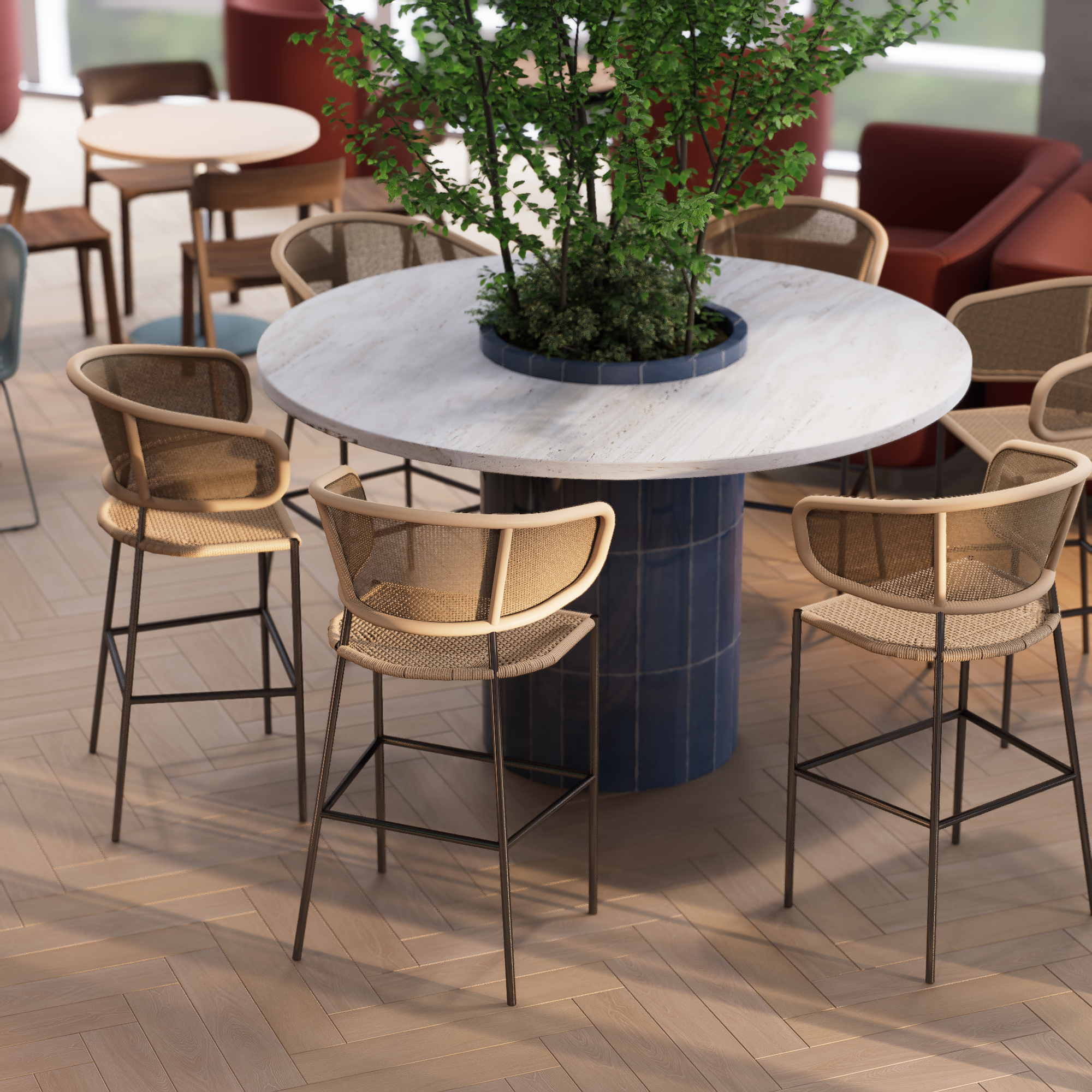 Round table with a large green plant in the center, surrounded by beige and tan chairs, in a modern indoor setting with wooden flooring and other seating areas in the background.