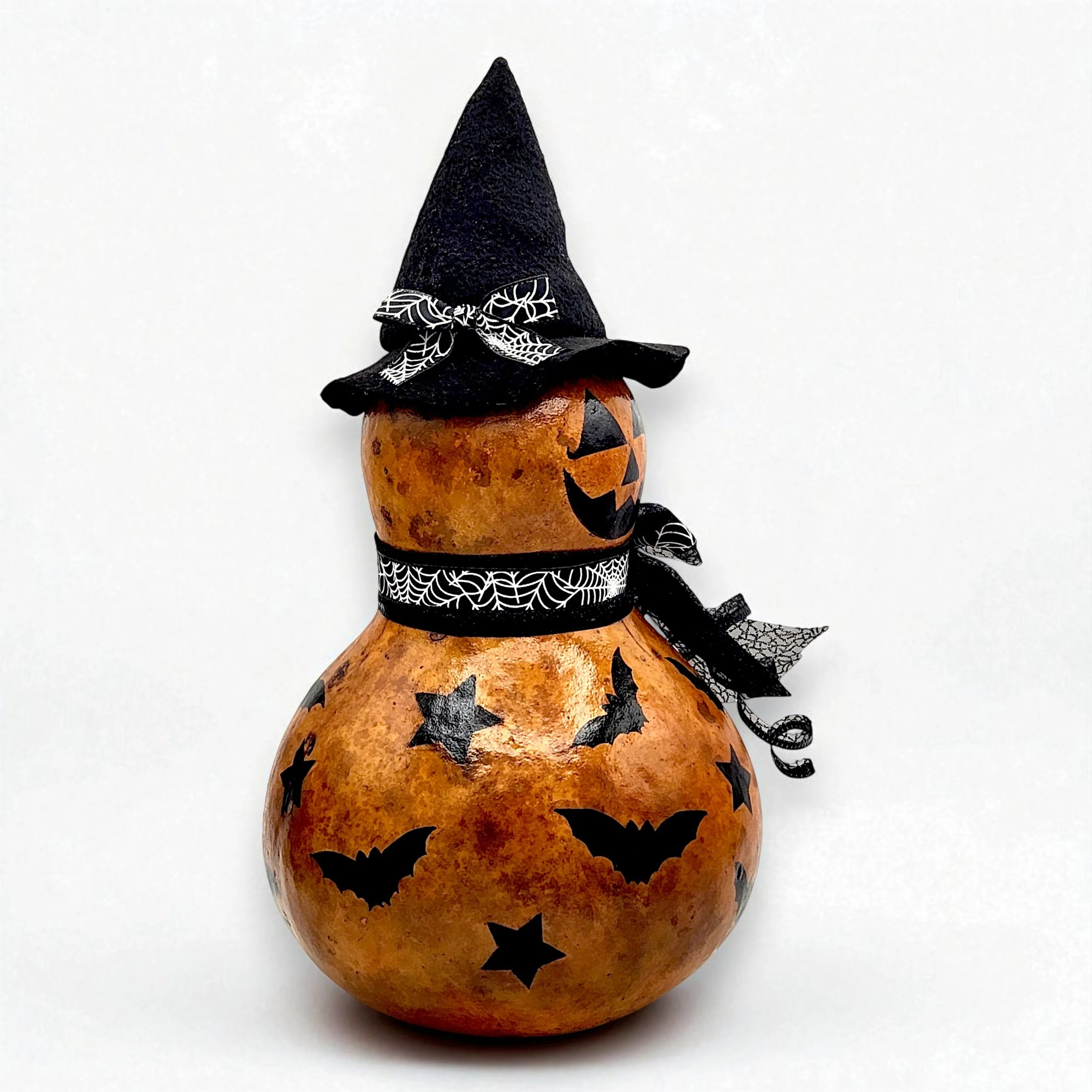 Side view of Jack-o-lantern gourd with Witch hat, fancy ribbons and bow on hat and covered with bats and stars.